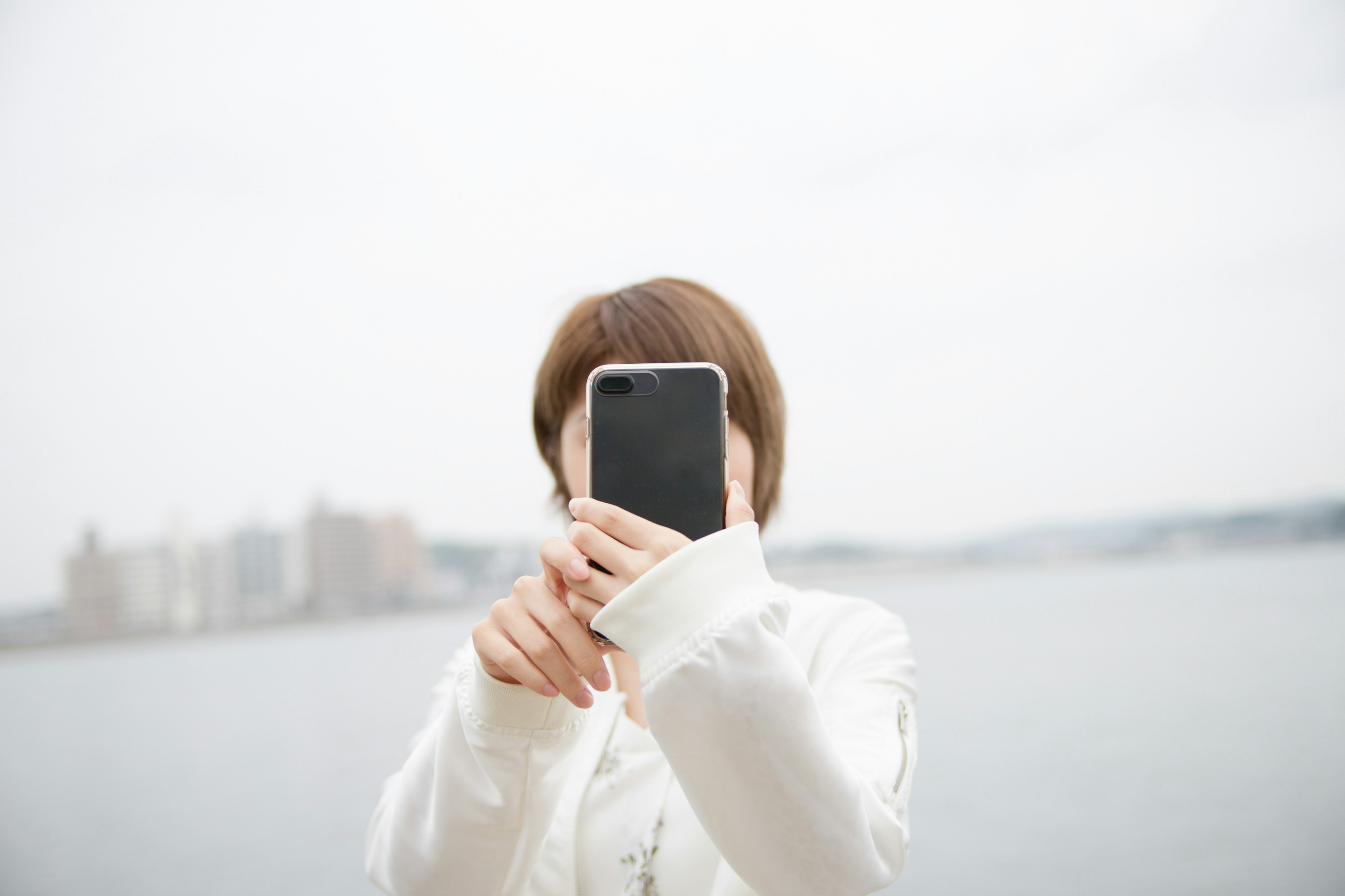 Eine Frau in weißer Kleidung, die ein Smartphone hält