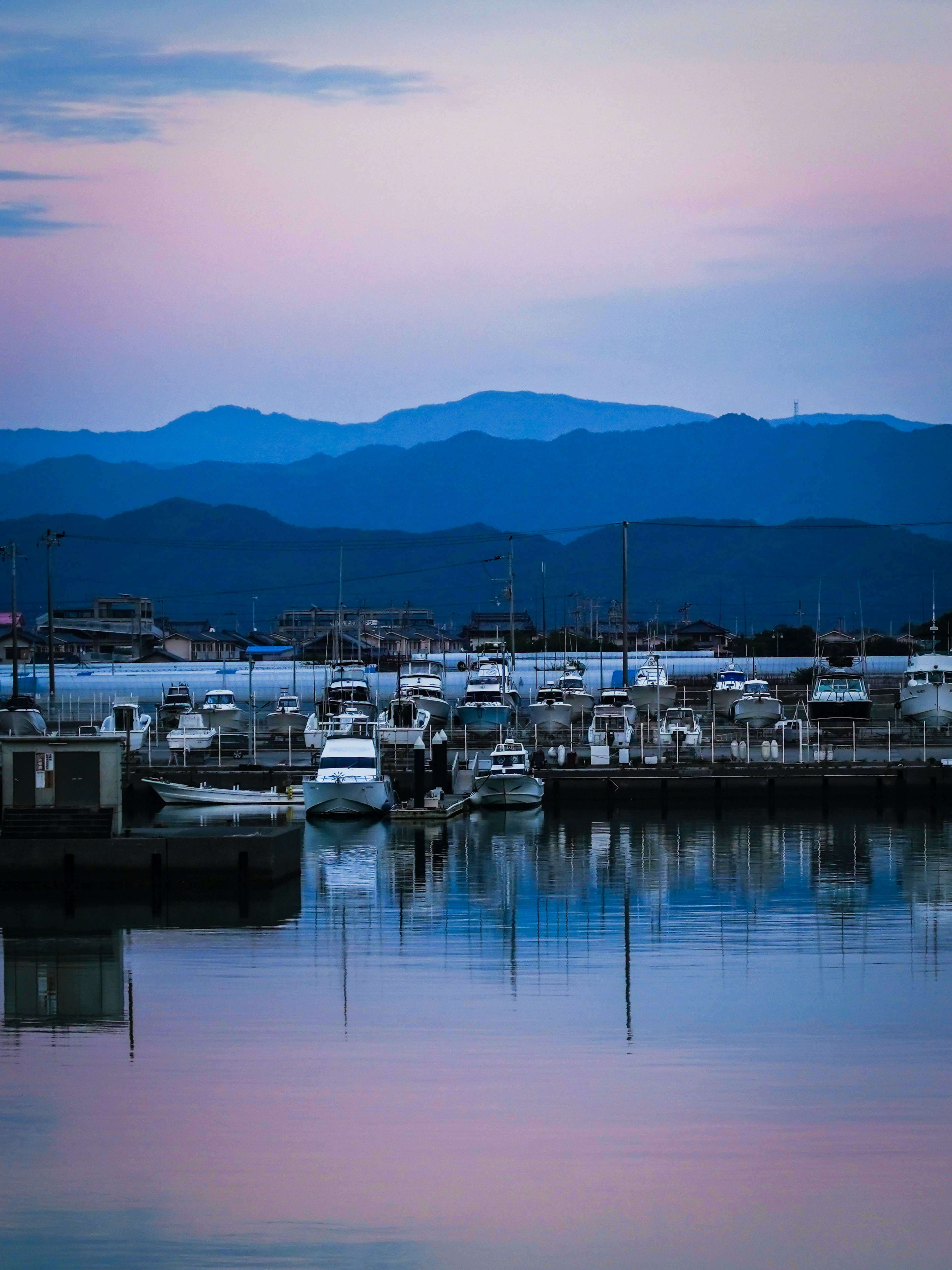 青い山々を背景にした静かな港の風景 船が停泊している