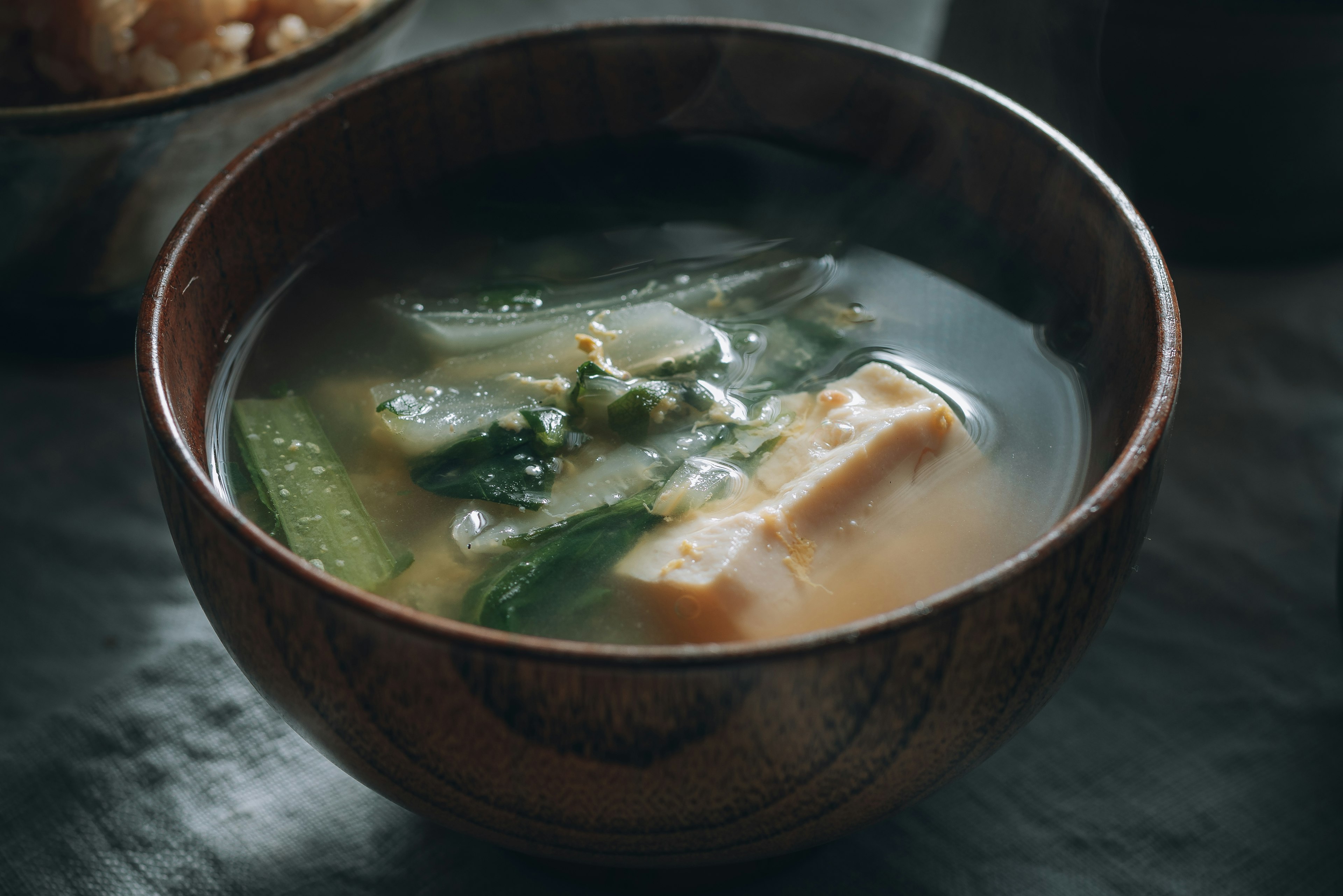 A wooden bowl filled with soup and vegetables