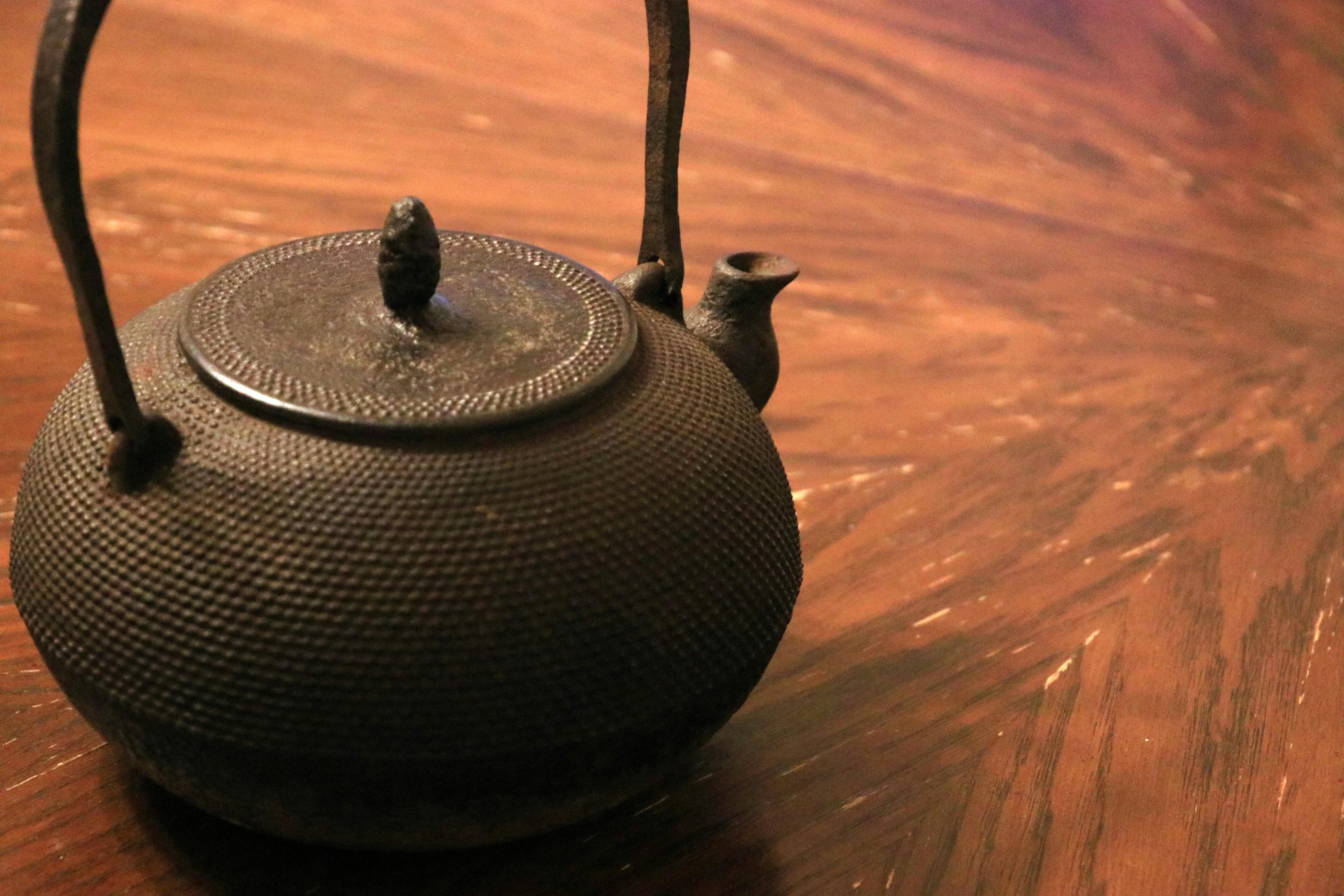 A black cast iron teapot on a wooden table