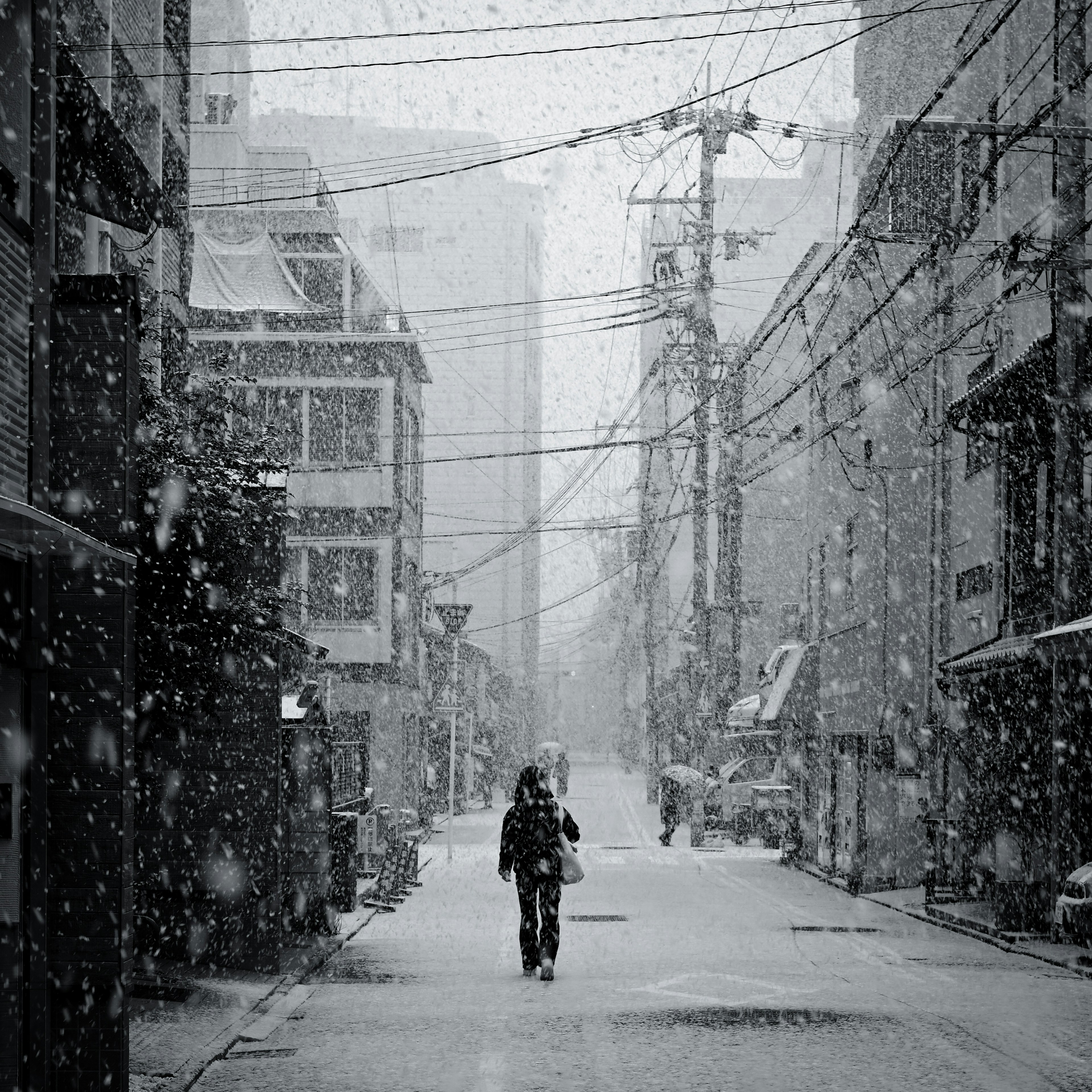 Foto in bianco e nero di una persona che cammina in una strada innevata