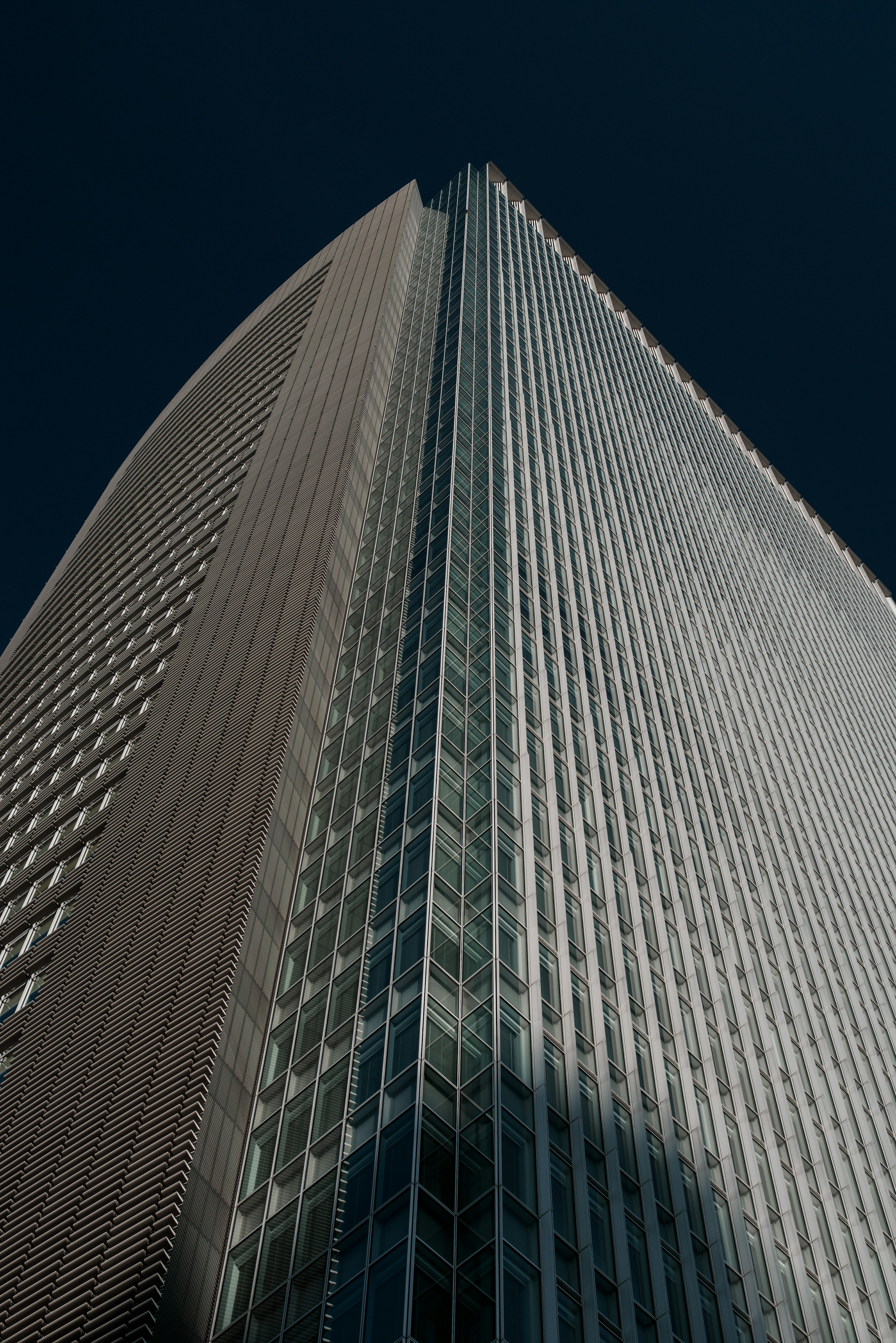 A photo looking up at a tall building showcasing modern design and prominent glass facade