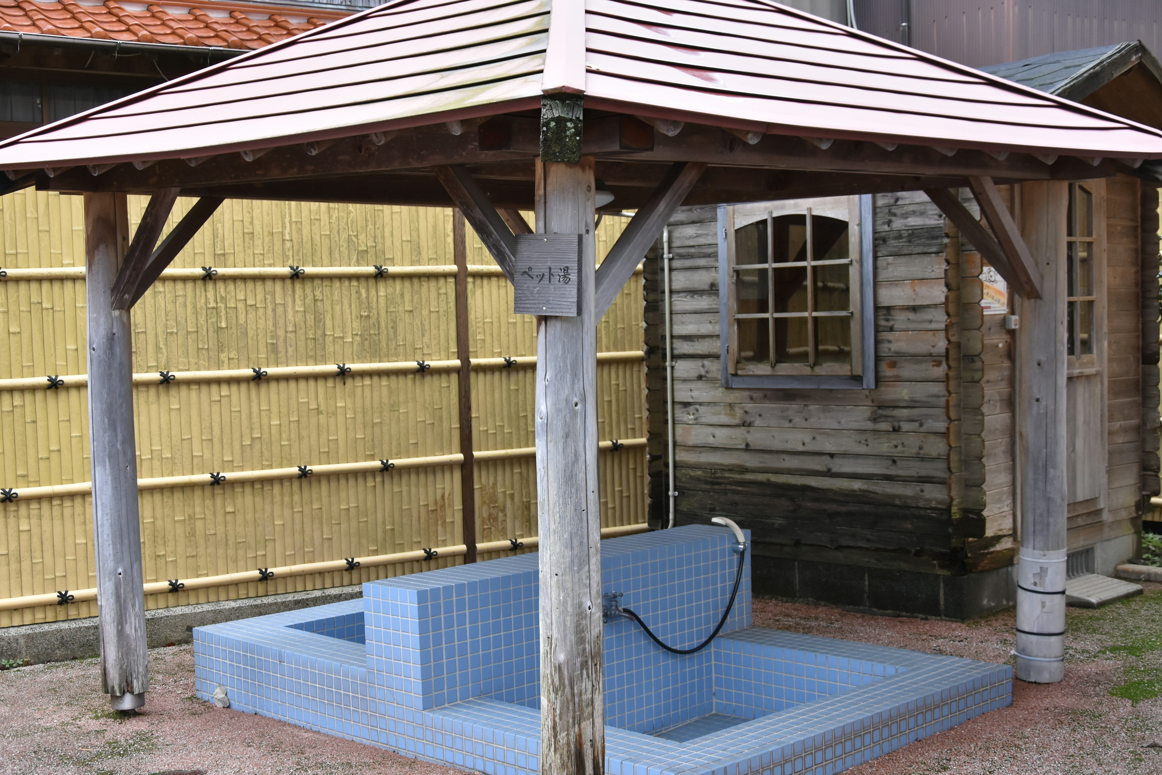 Outdoor spa area with a wooden roof and blue tiled bathing space