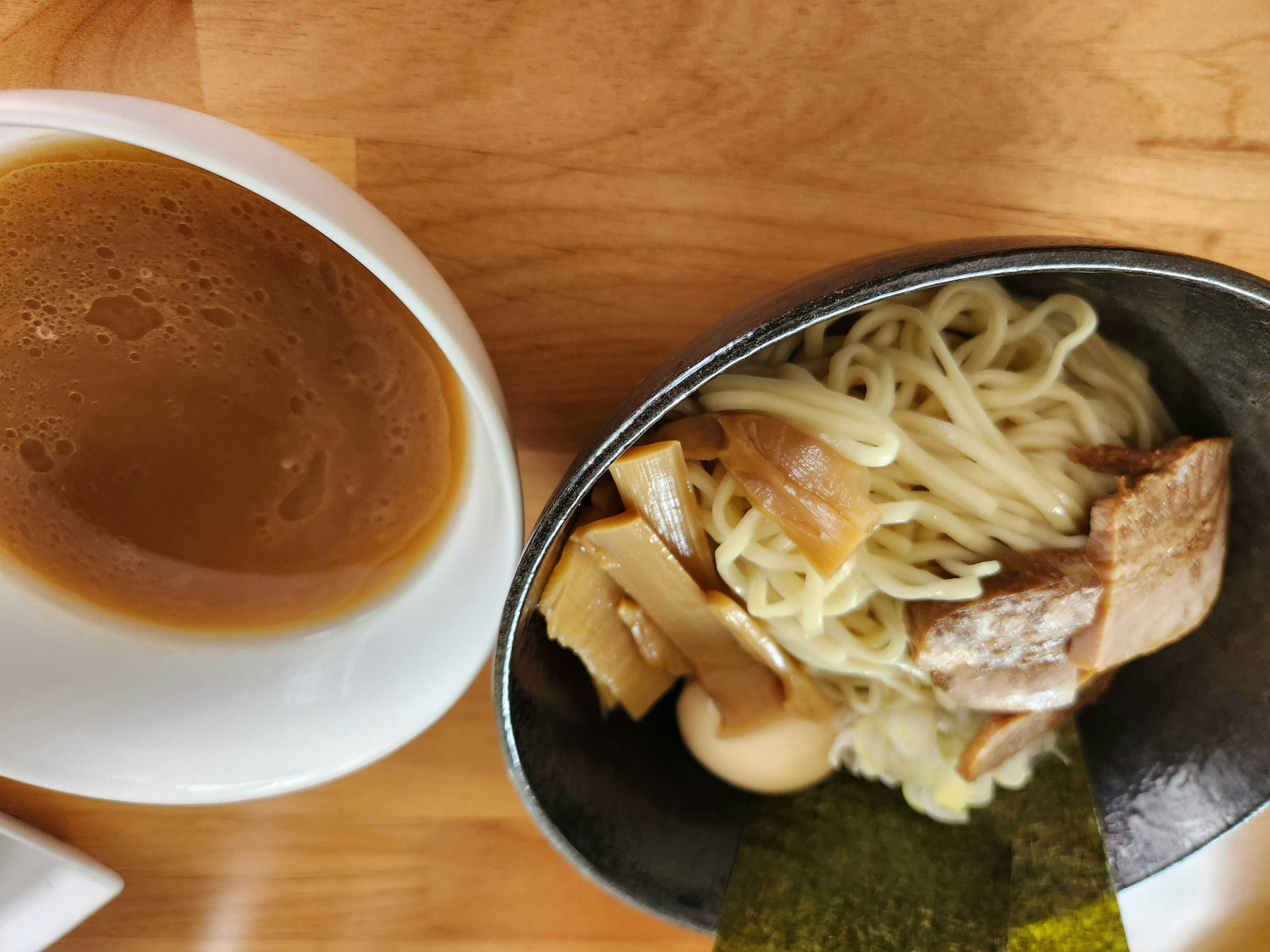 スープと麺が盛られた皿とトッピングの肉や海苔が見える