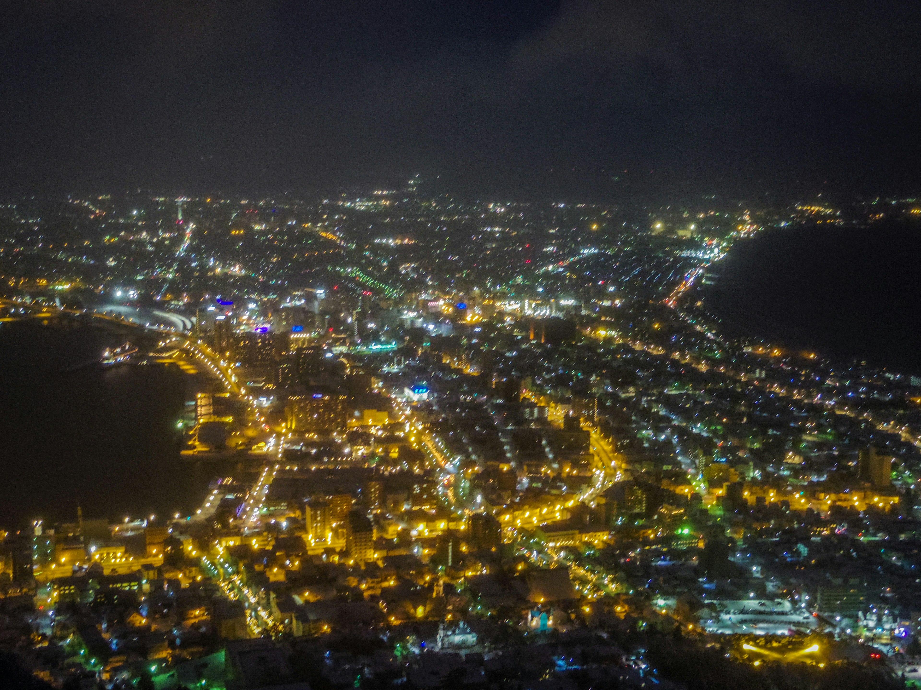 Vue aérienne d'une ville la nuit avec des lampadaires lumineux et le littoral