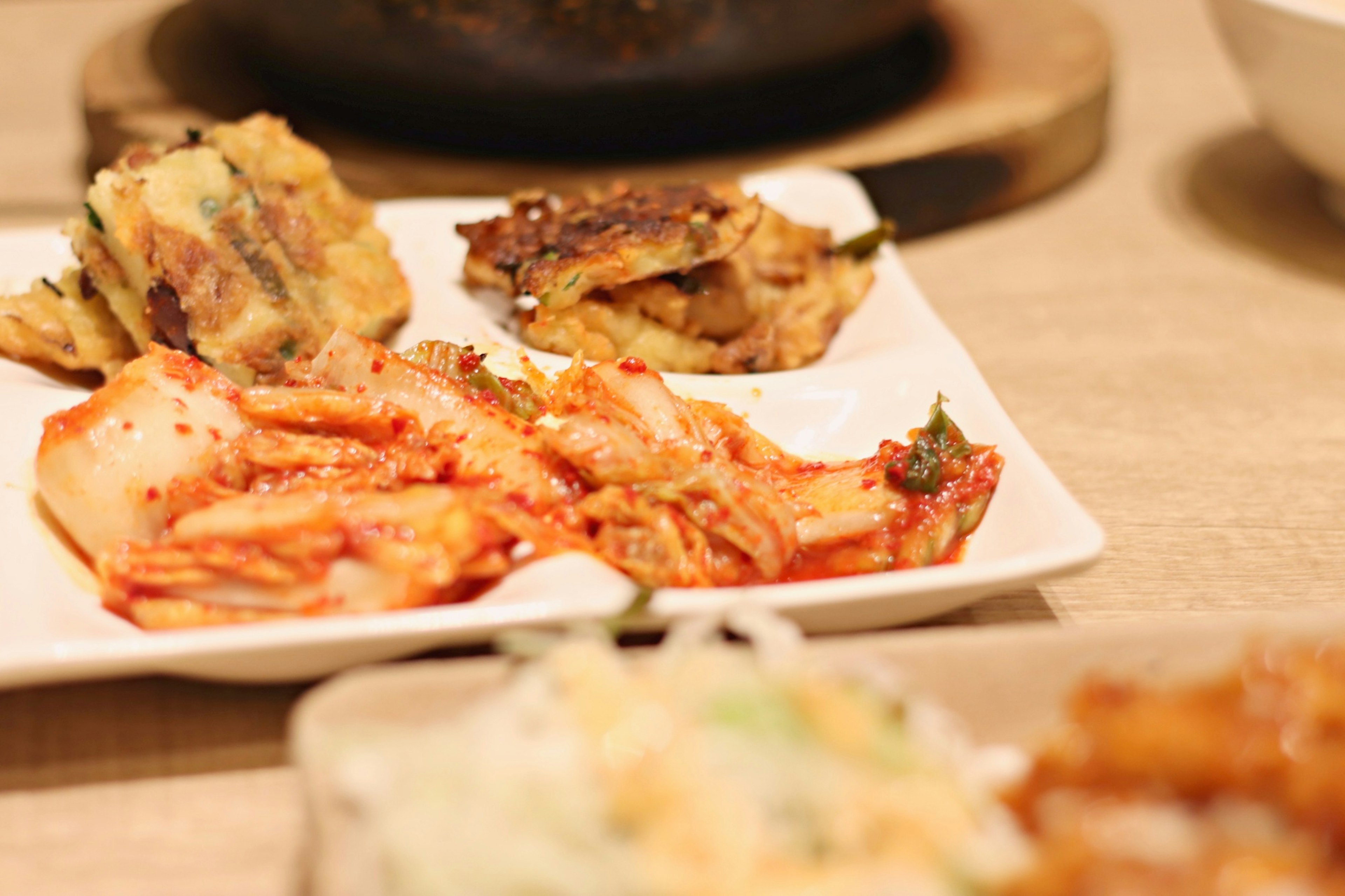 A plate of Korean side dishes featuring kimchi and vegetable pancakes