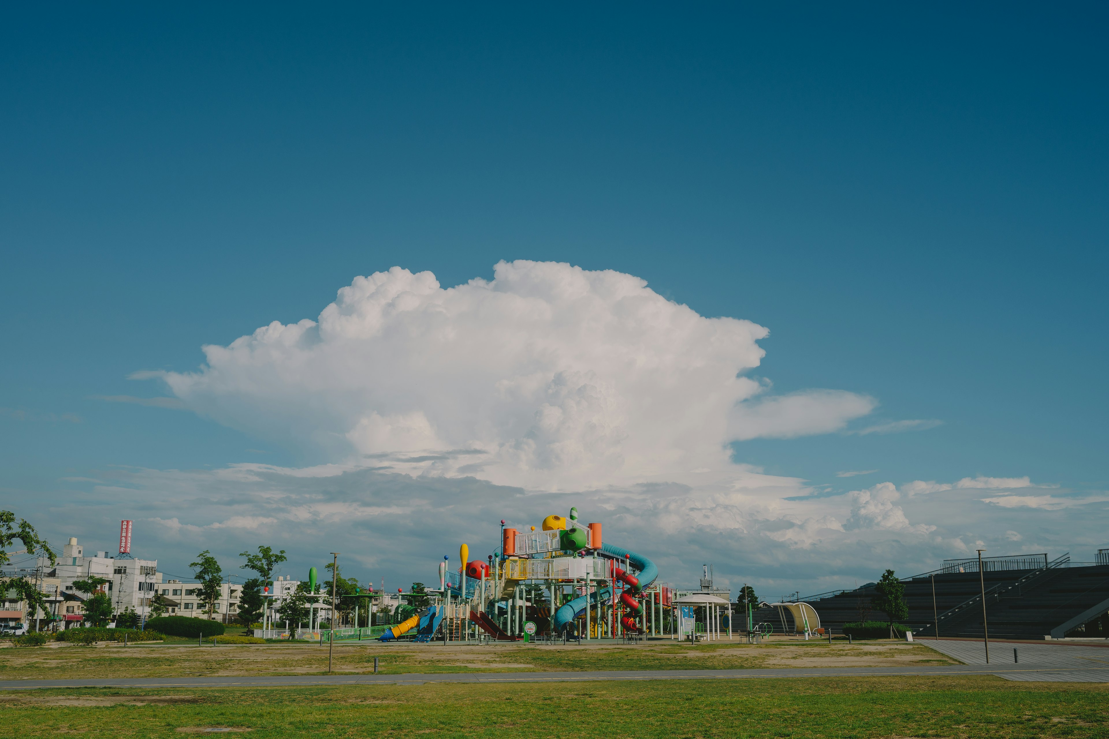 Taman bermain berwarna-warni di bawah langit biru dengan awan besar