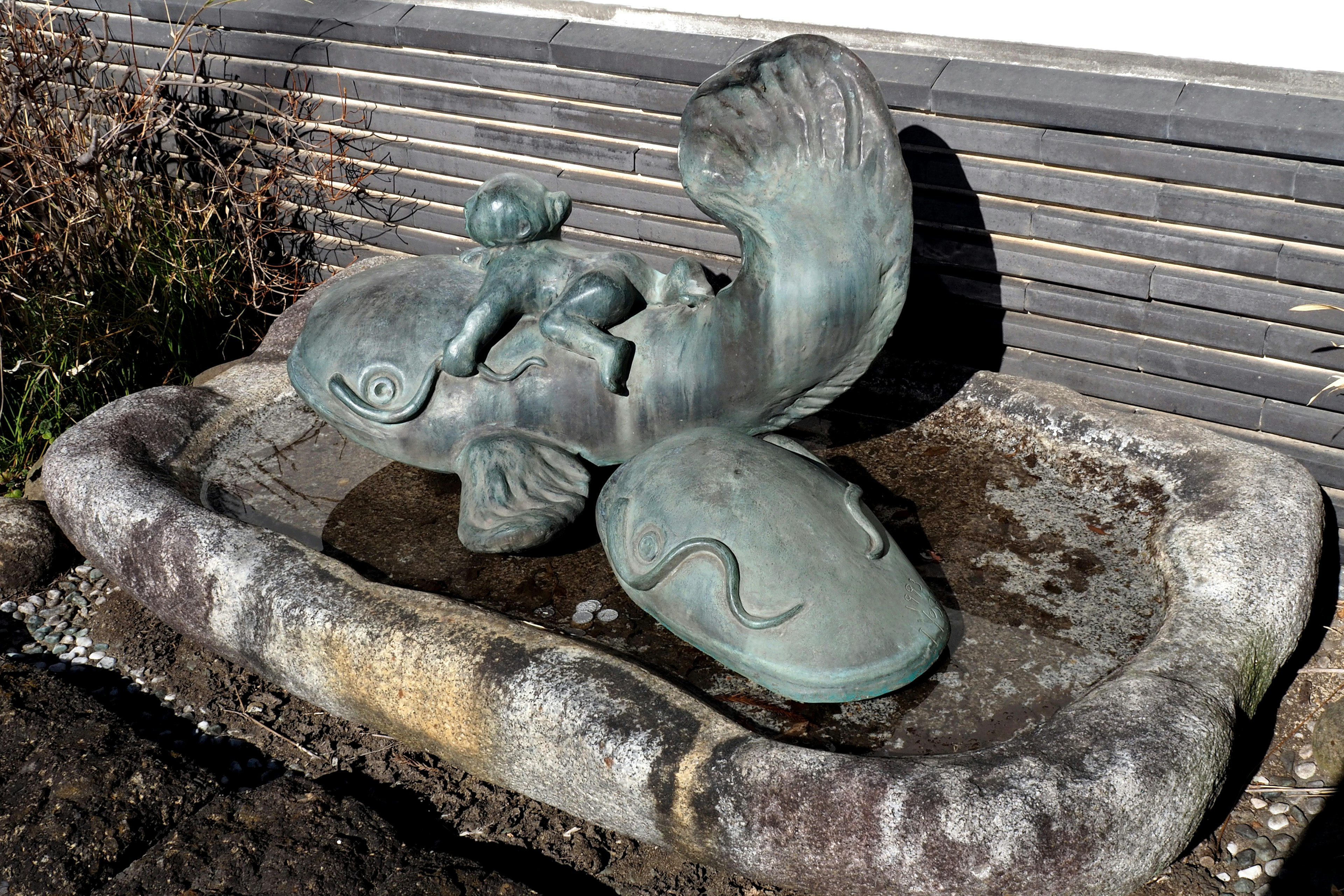 Bronzeskulptur eines Kindes, das auf einem Fisch sitzt