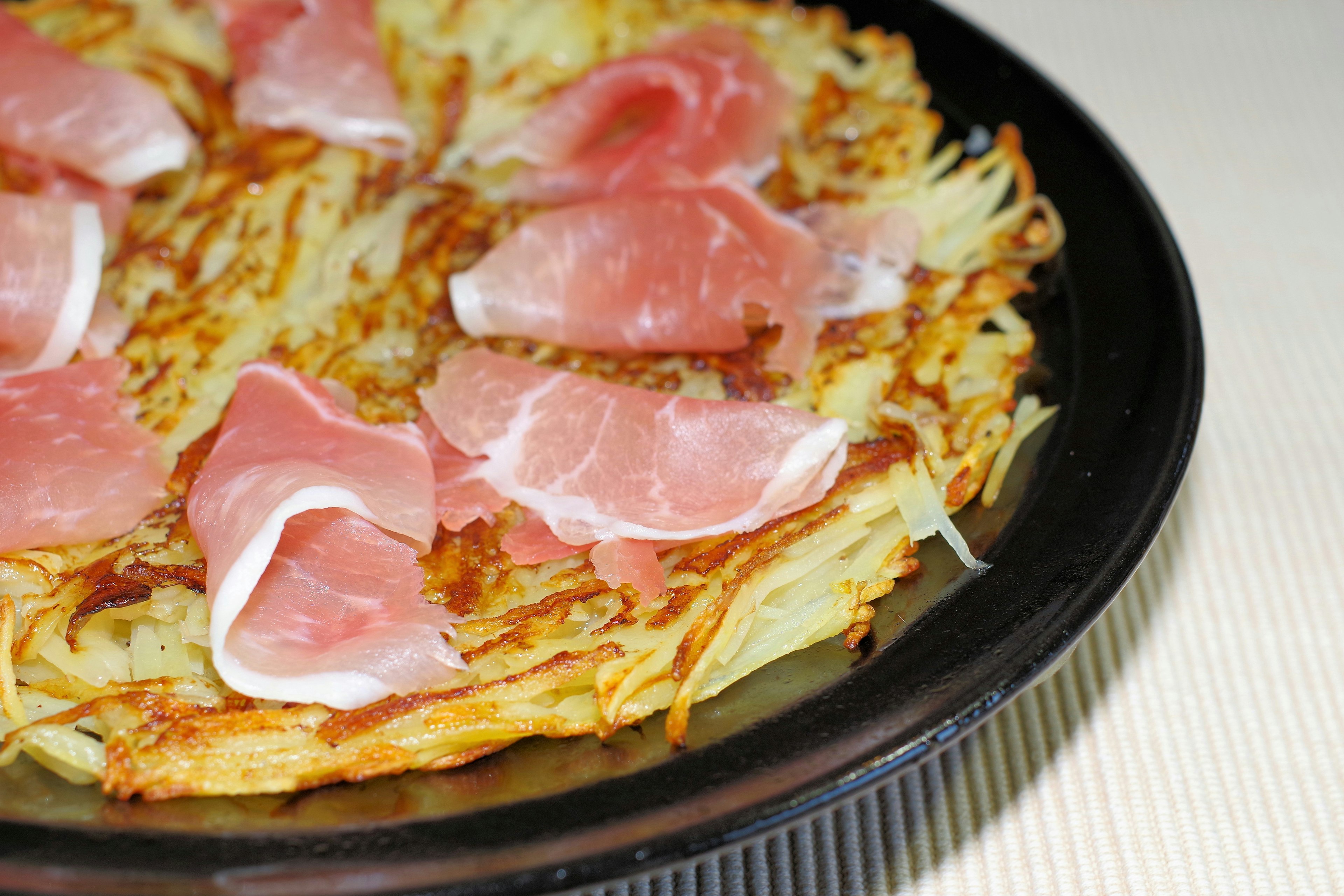 Hidangan yang terdiri dari hash brown dengan irisan prosciutto di atasnya