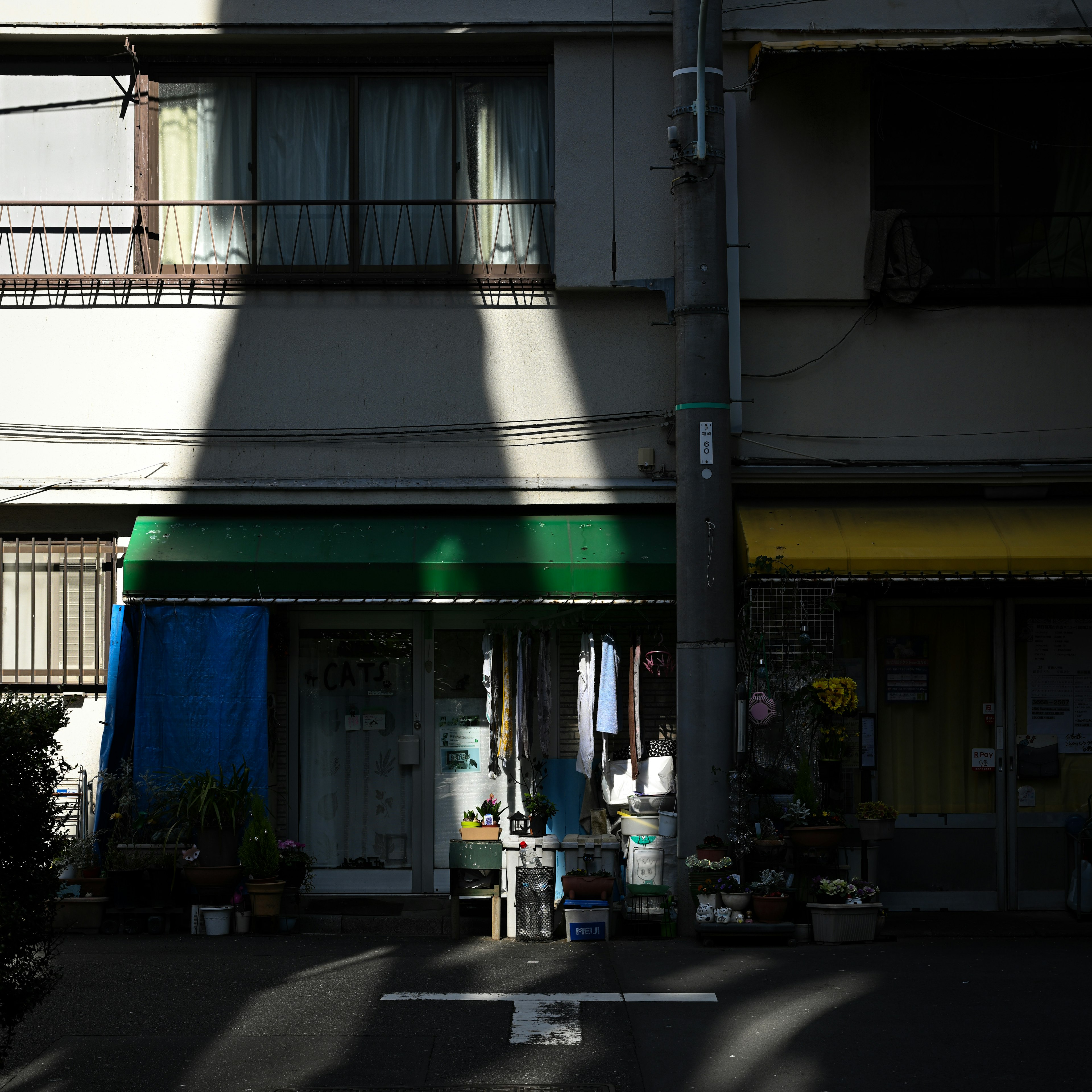 青いカーテンと緑のテントのある店舗の外観