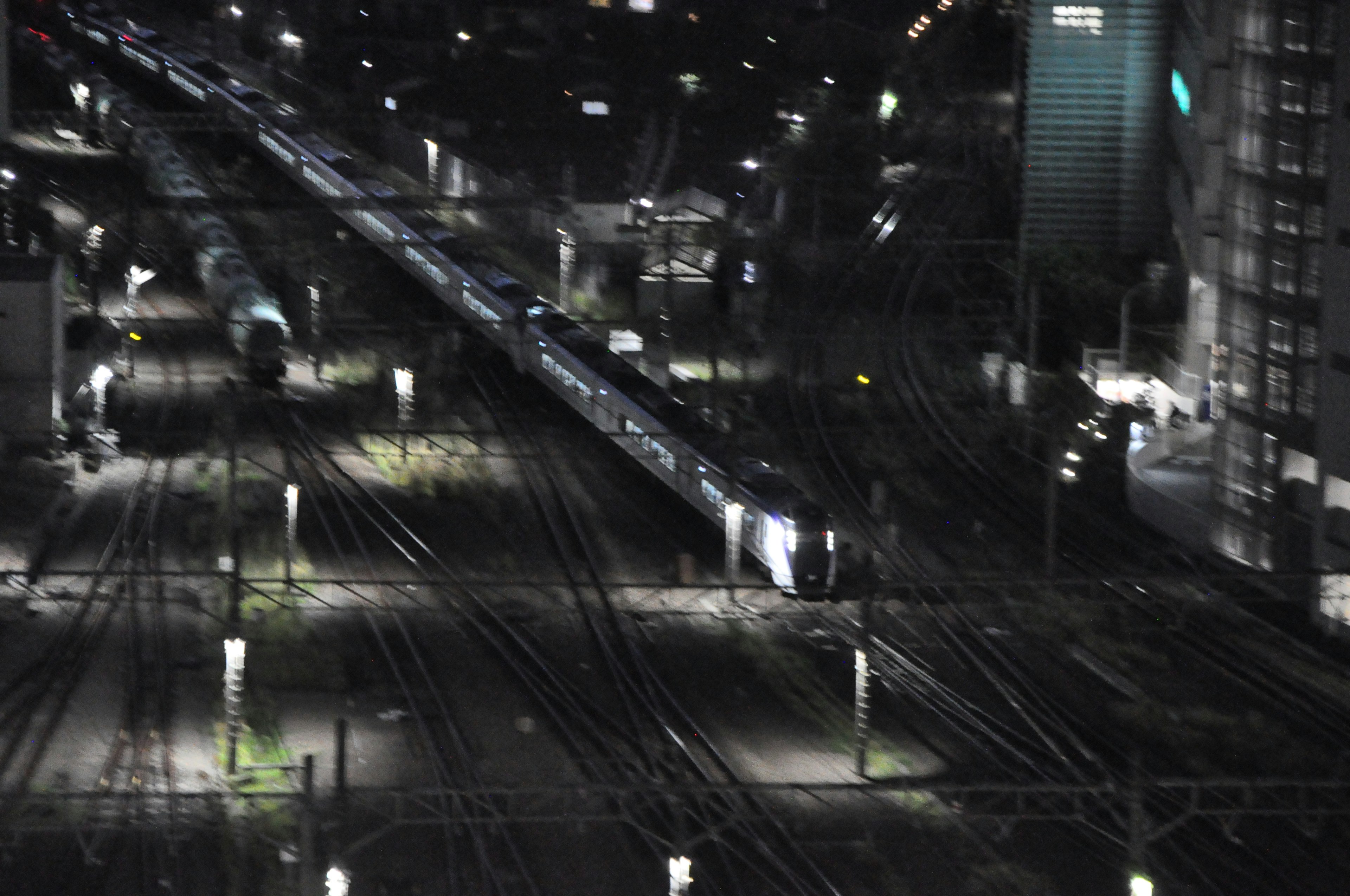 Nighttime railway station scene featuring tracks and train lights