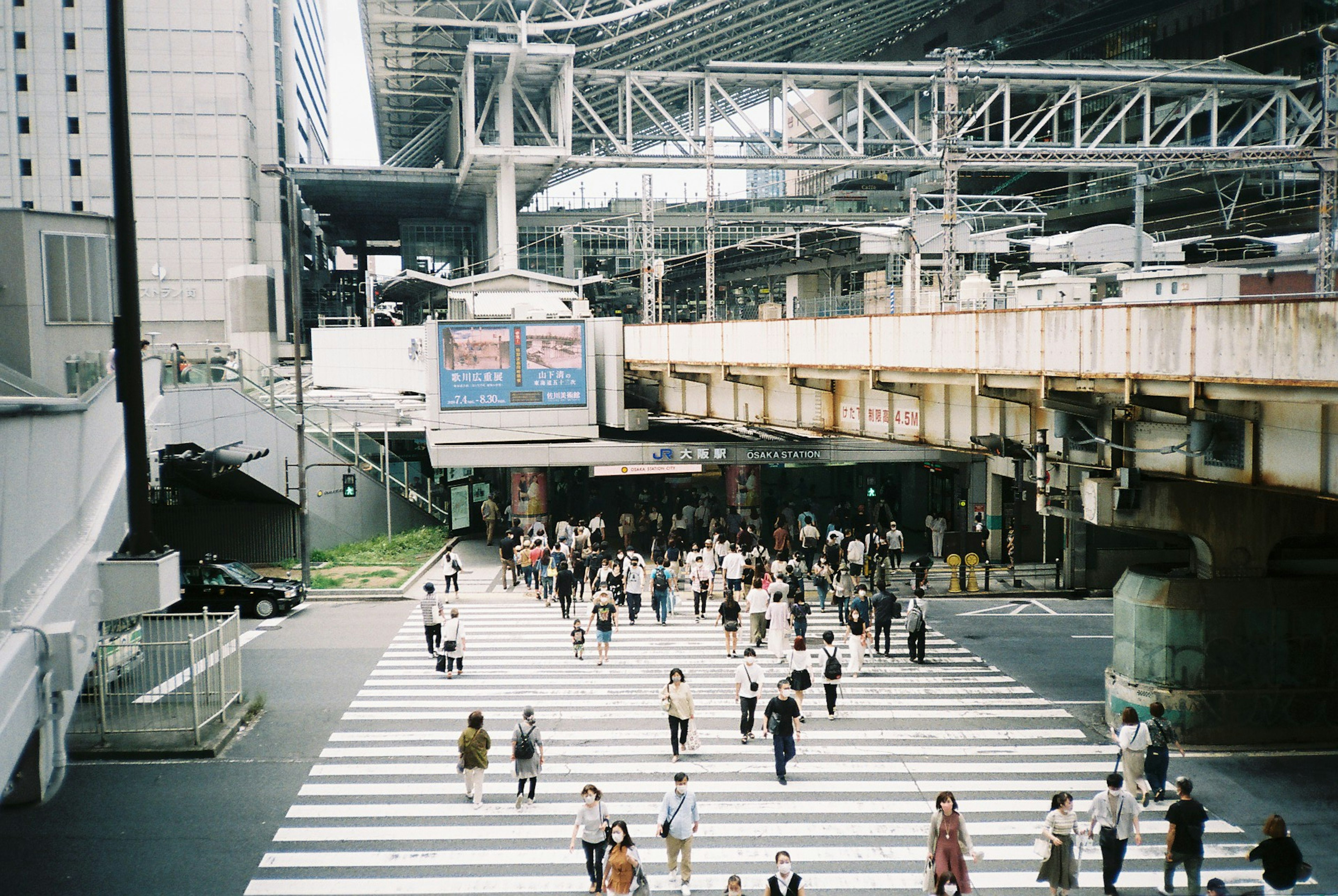 城市場景，人們正在過馬路，鐵路橋和建築物在背景中