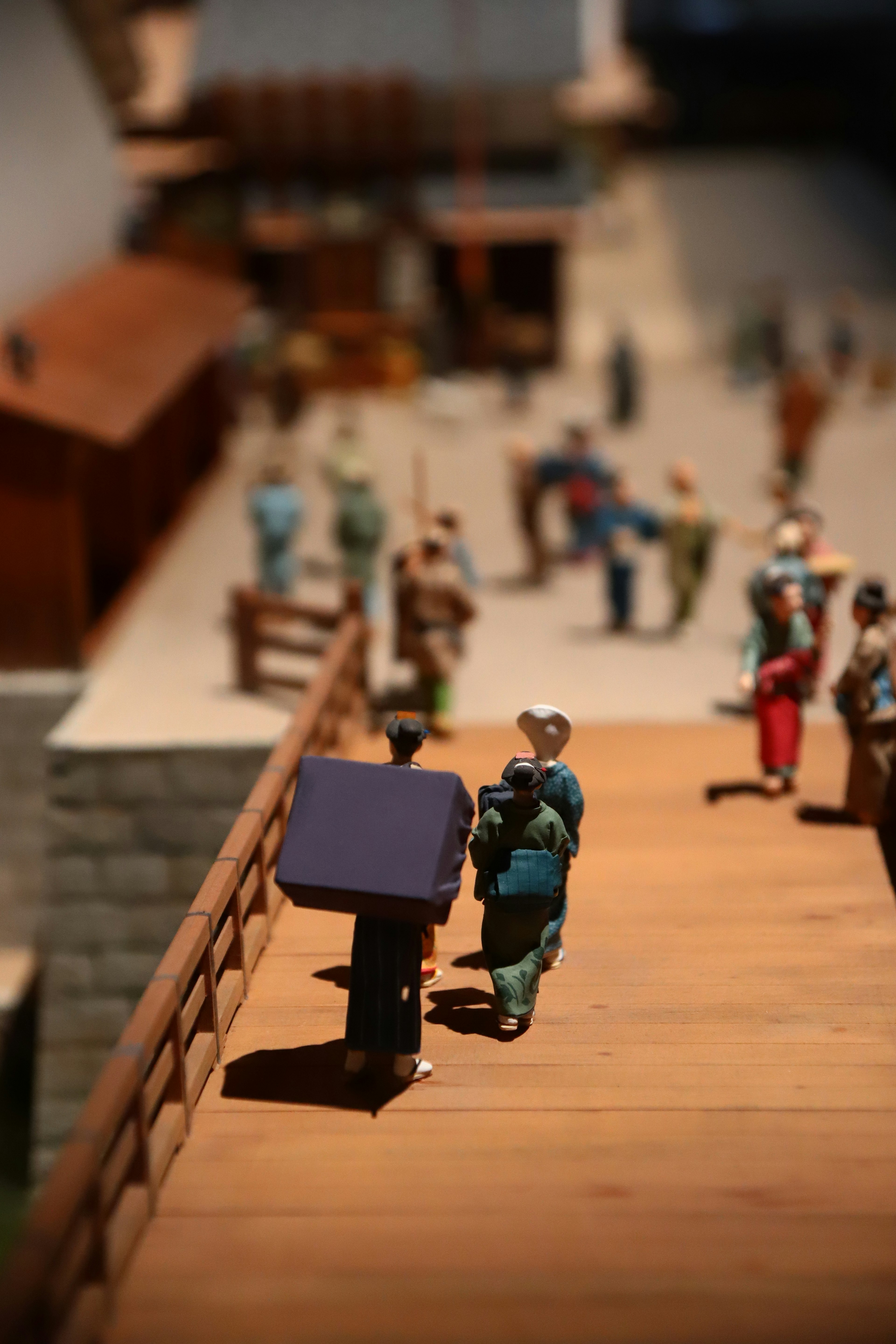 Small figurines on a wooden bridge with people in the background