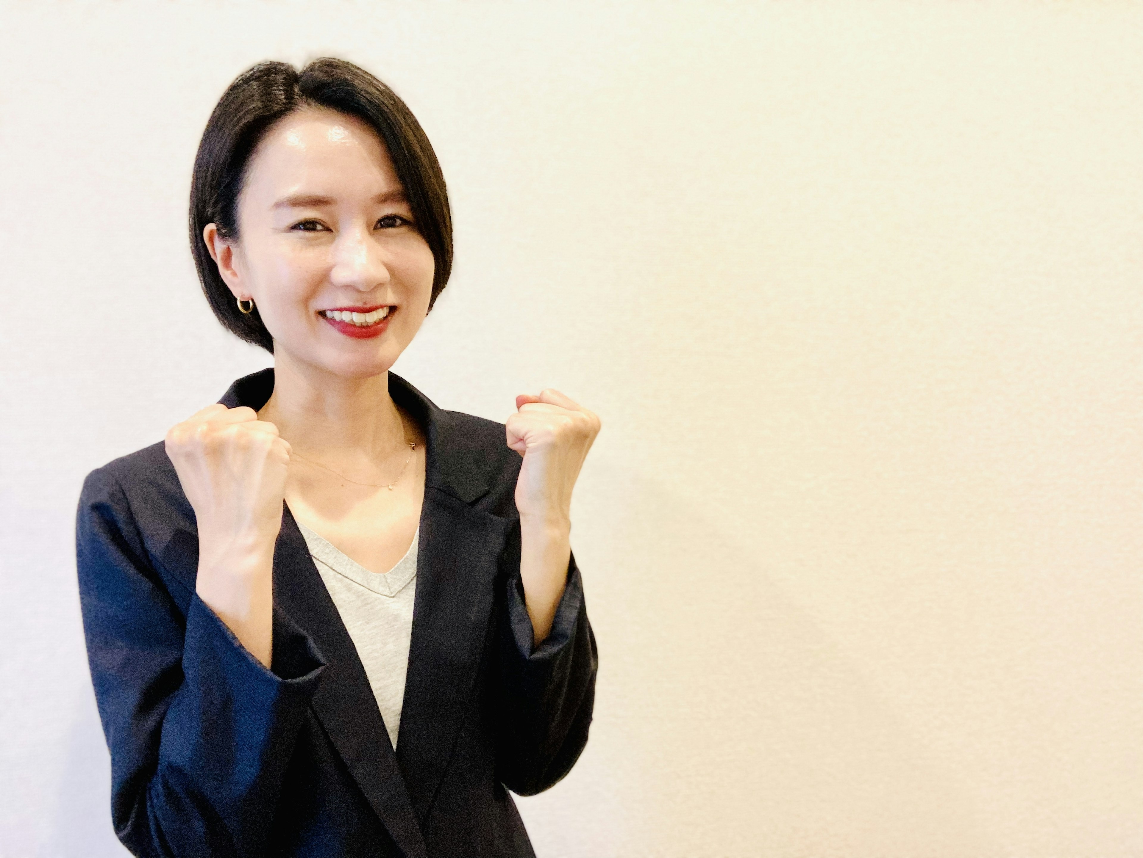 Woman in a black jacket smiling with clenched fists