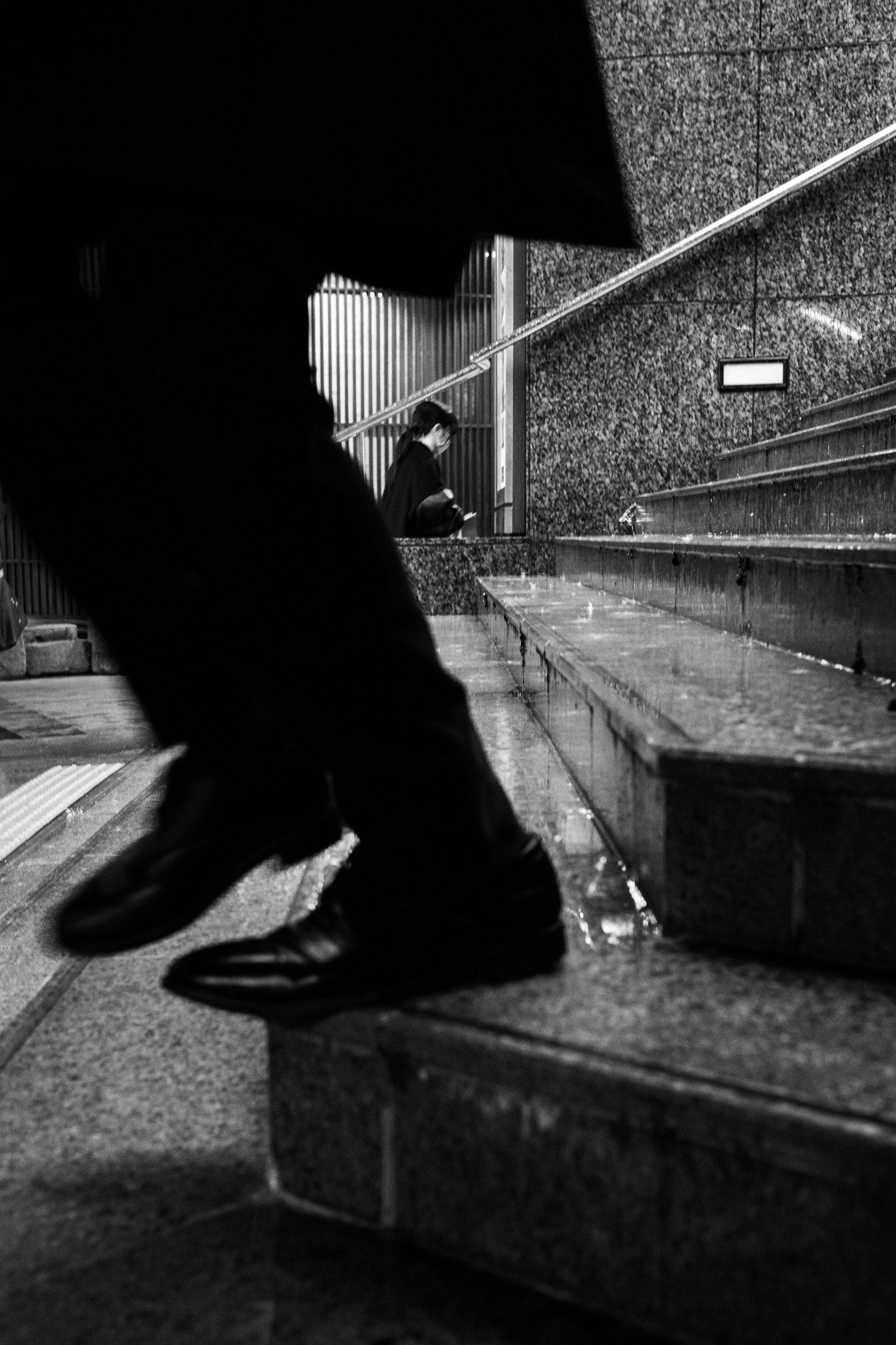 Black and white photo of a man stepping down stairs