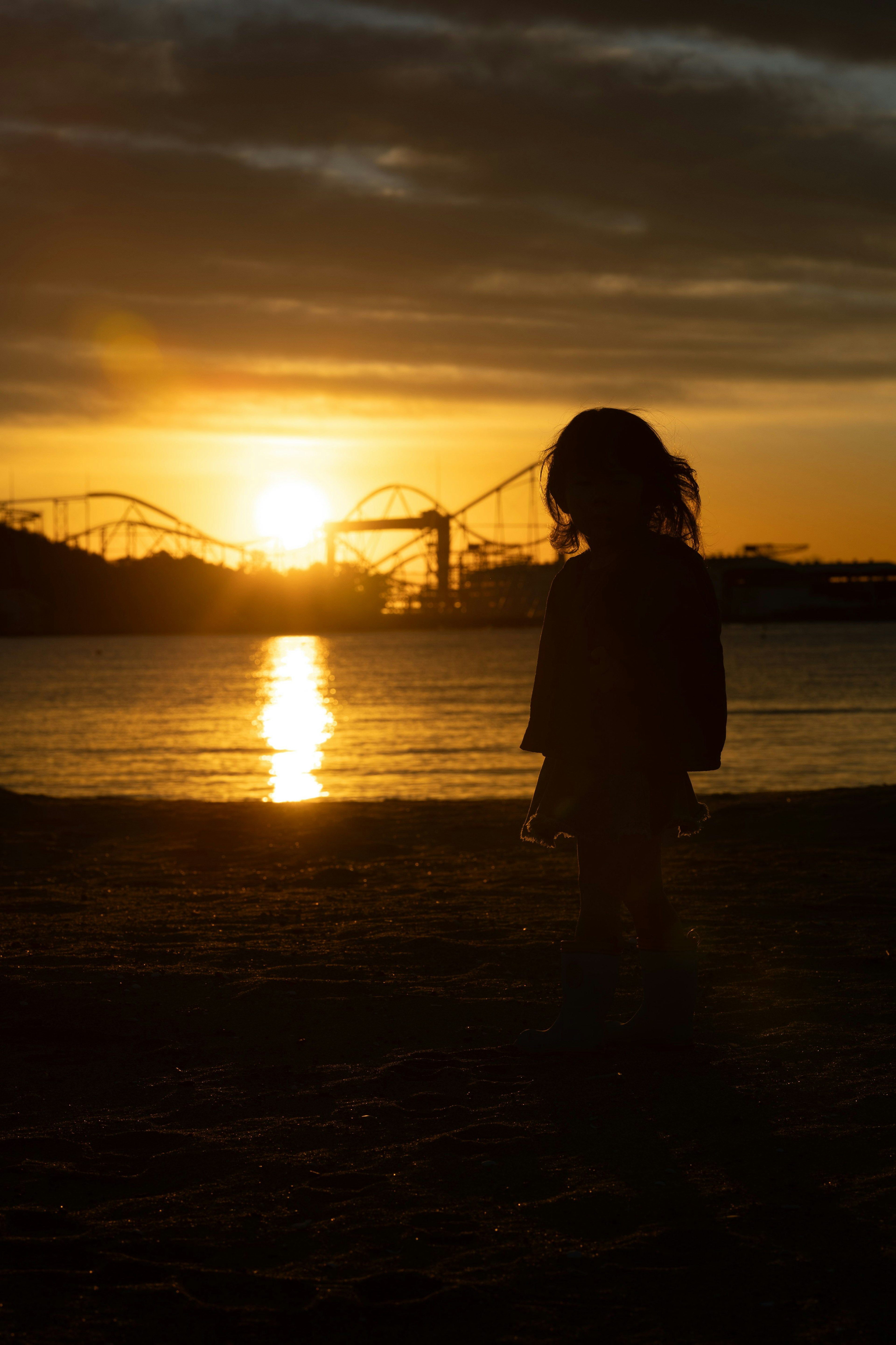 Silhouette d'un enfant contre un coucher de soleil sur la plage Roue de la fortune en arrière-plan