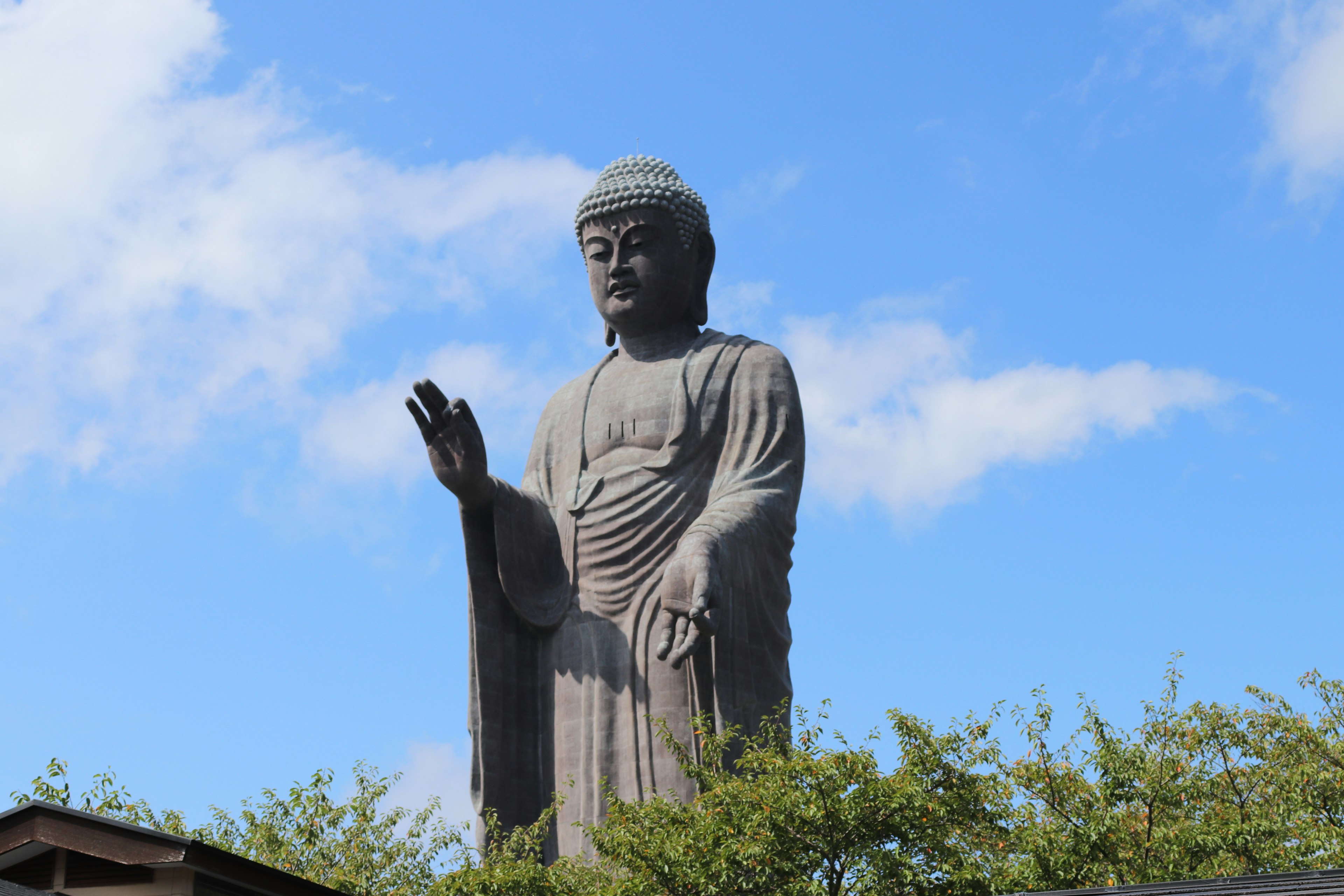 Giant Buddha statue standing under blue sky