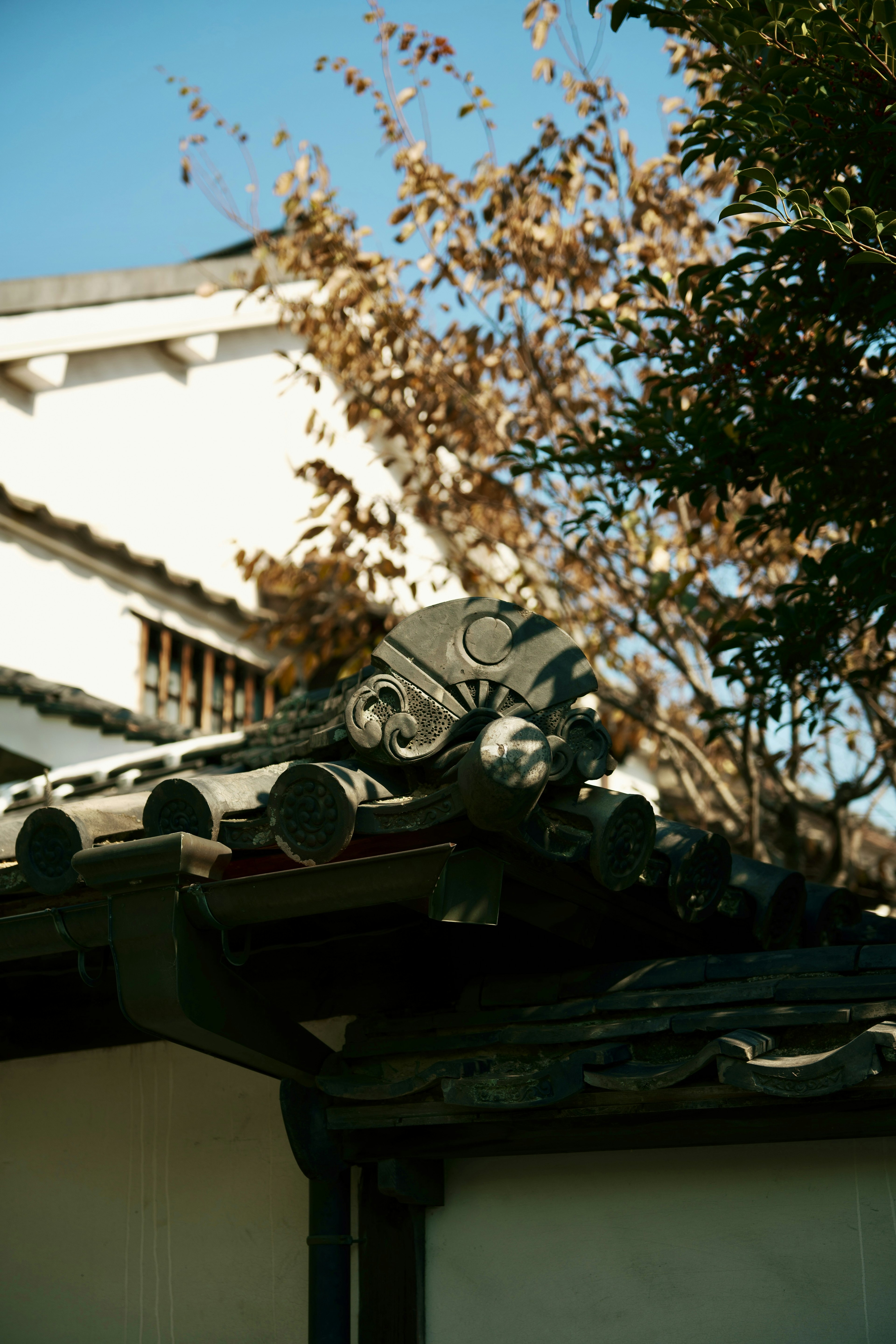 Traditional Japanese building featuring roof tiles and autumn leaves