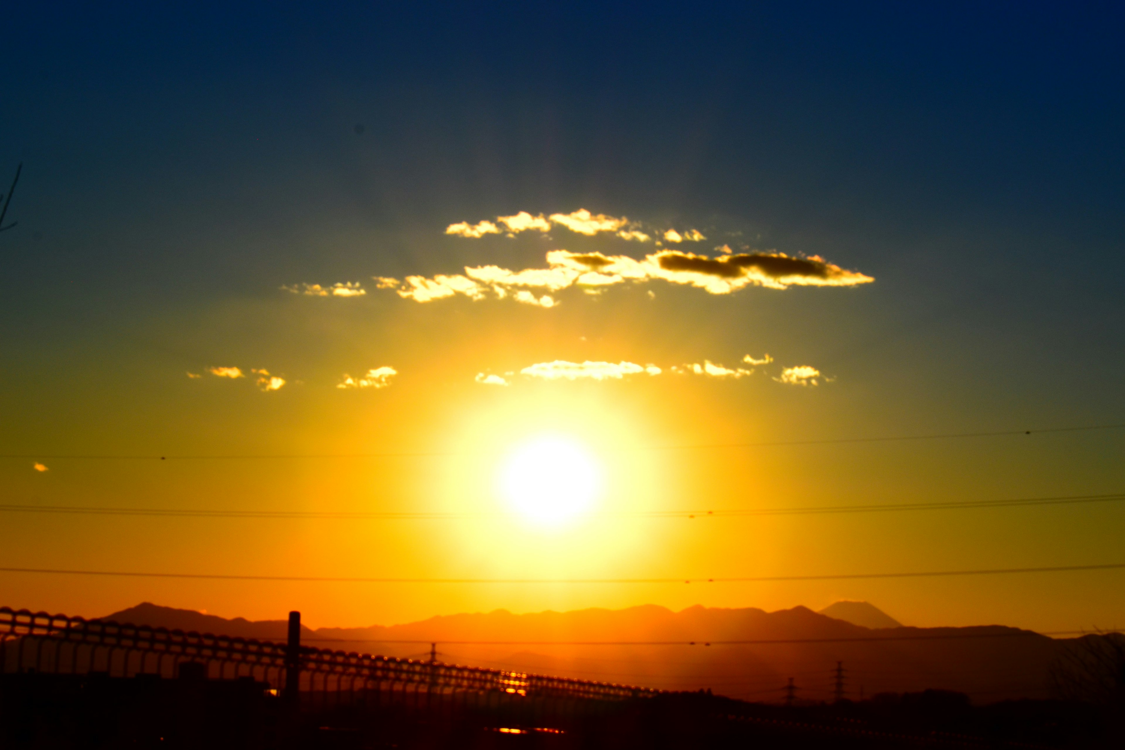 Hermosa puesta de sol iluminando montañas con nubes en un cielo azul y luz naranja