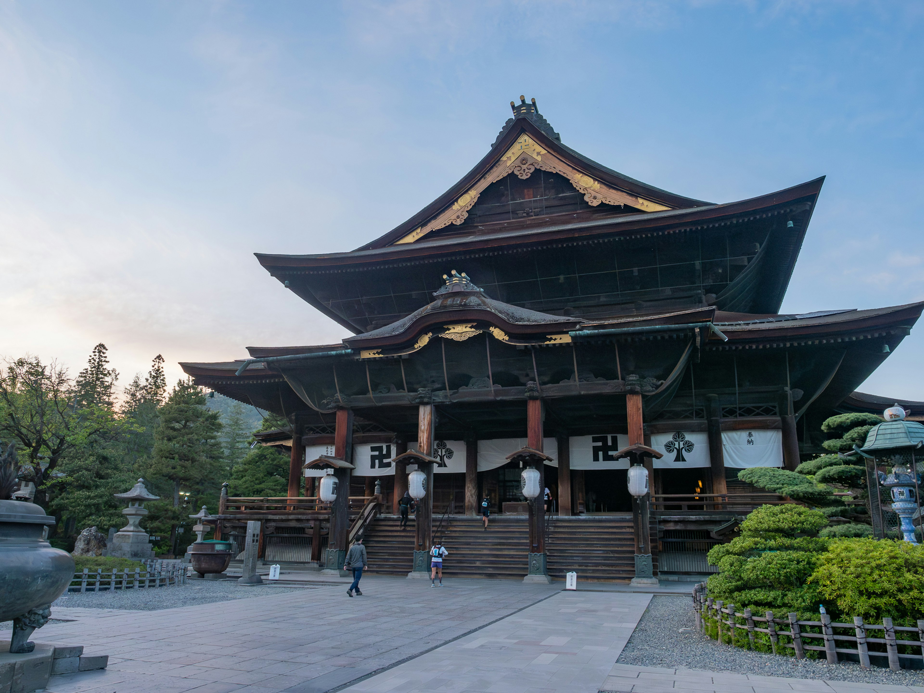 Exterior de un hermoso templo japonés con jardín verde y faroles de piedra