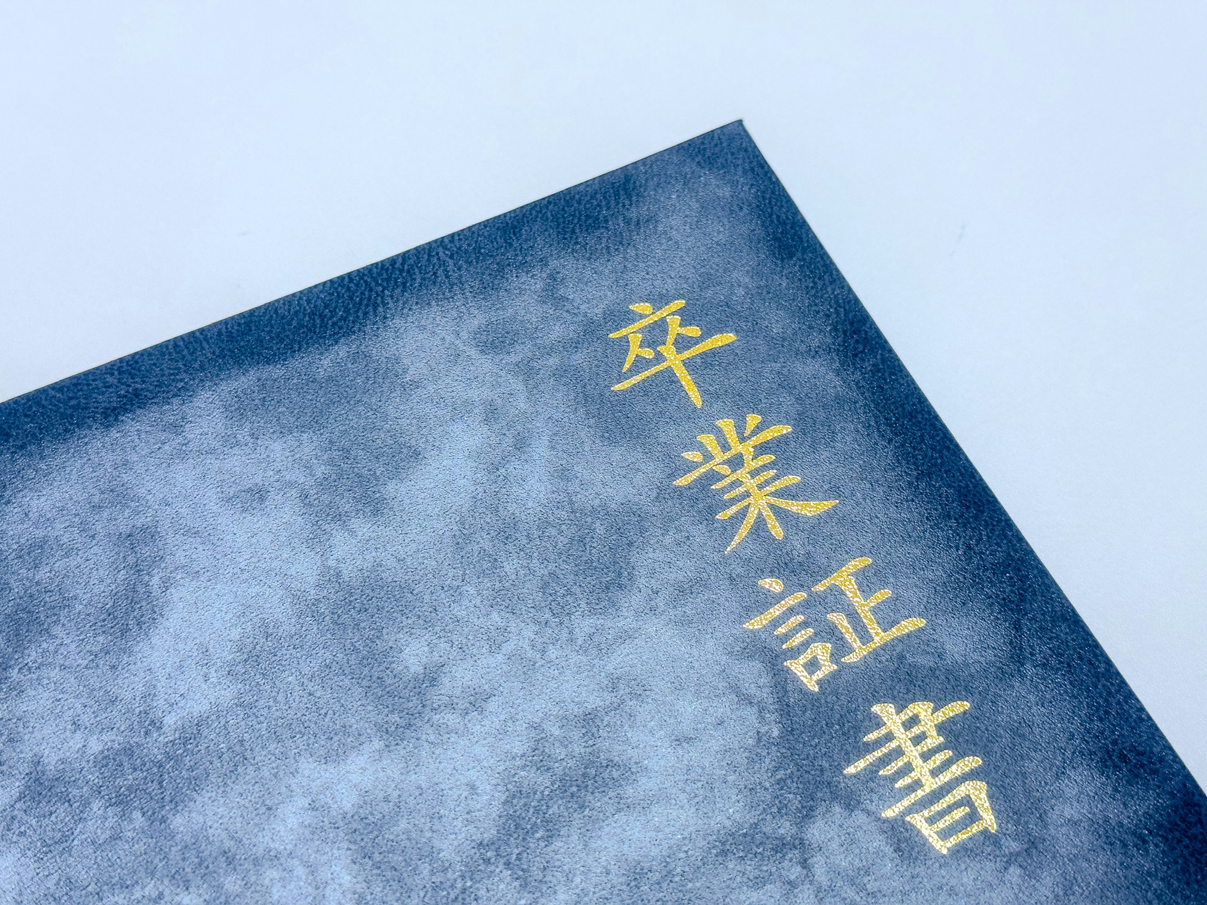 A blue graduation certificate cover with gold lettering