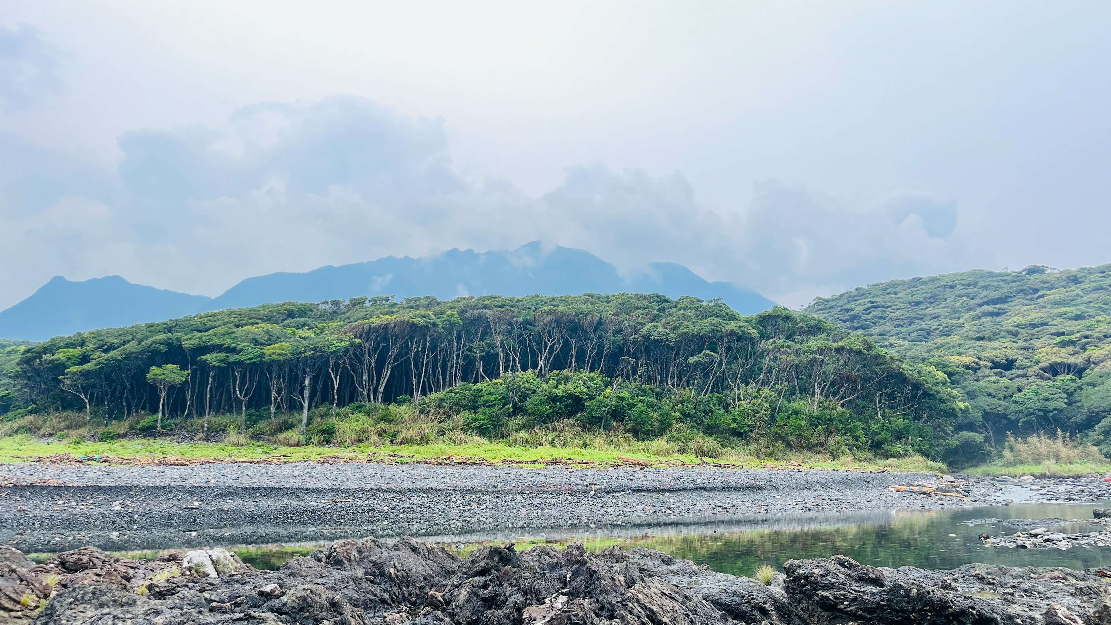 Pemandangan pulau yang subur dengan gunung yang terlihat di kejauhan