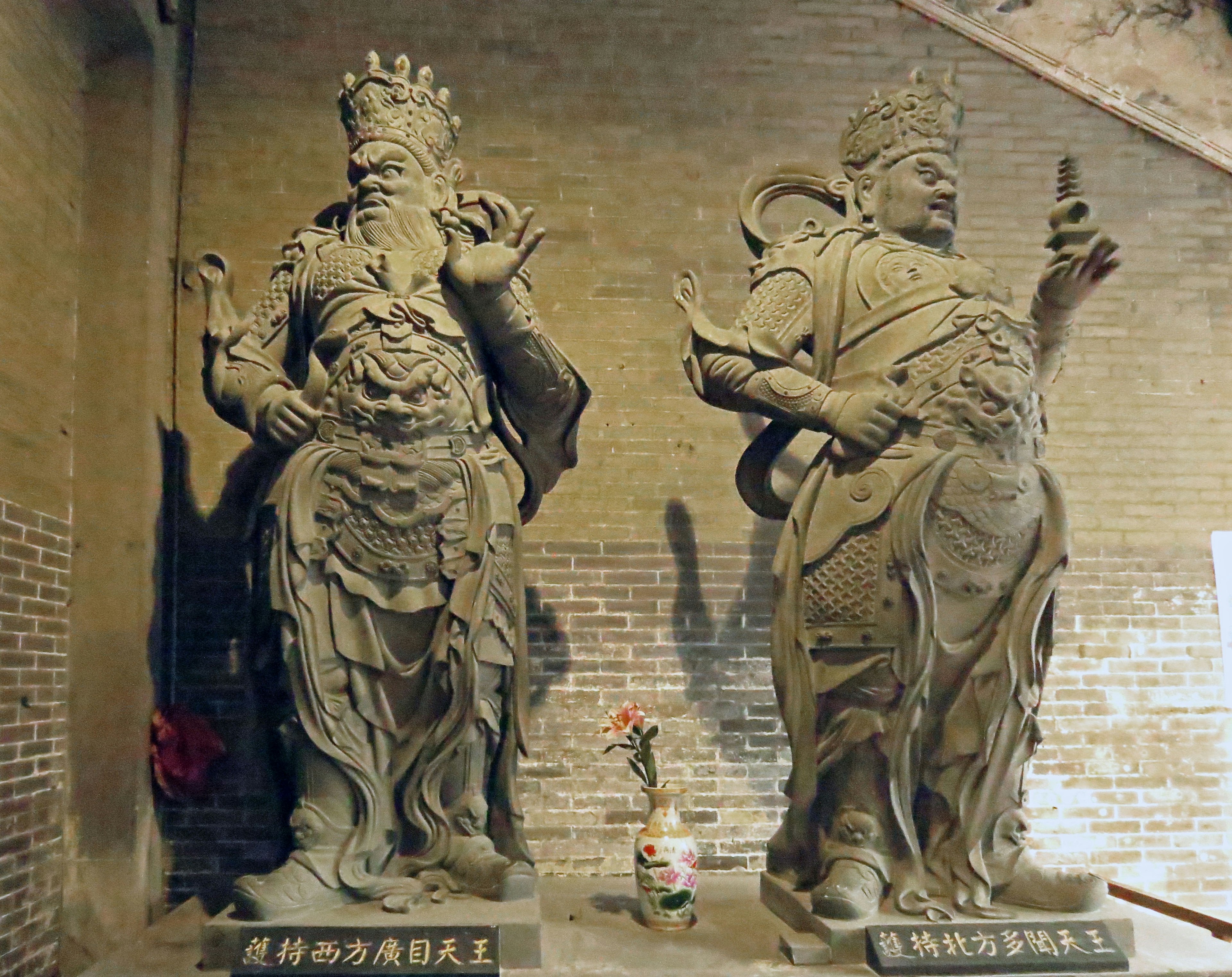 Image de deux statues en pierre se tenant côte à côte avec des sculptures détaillées et des vêtements distinctifs