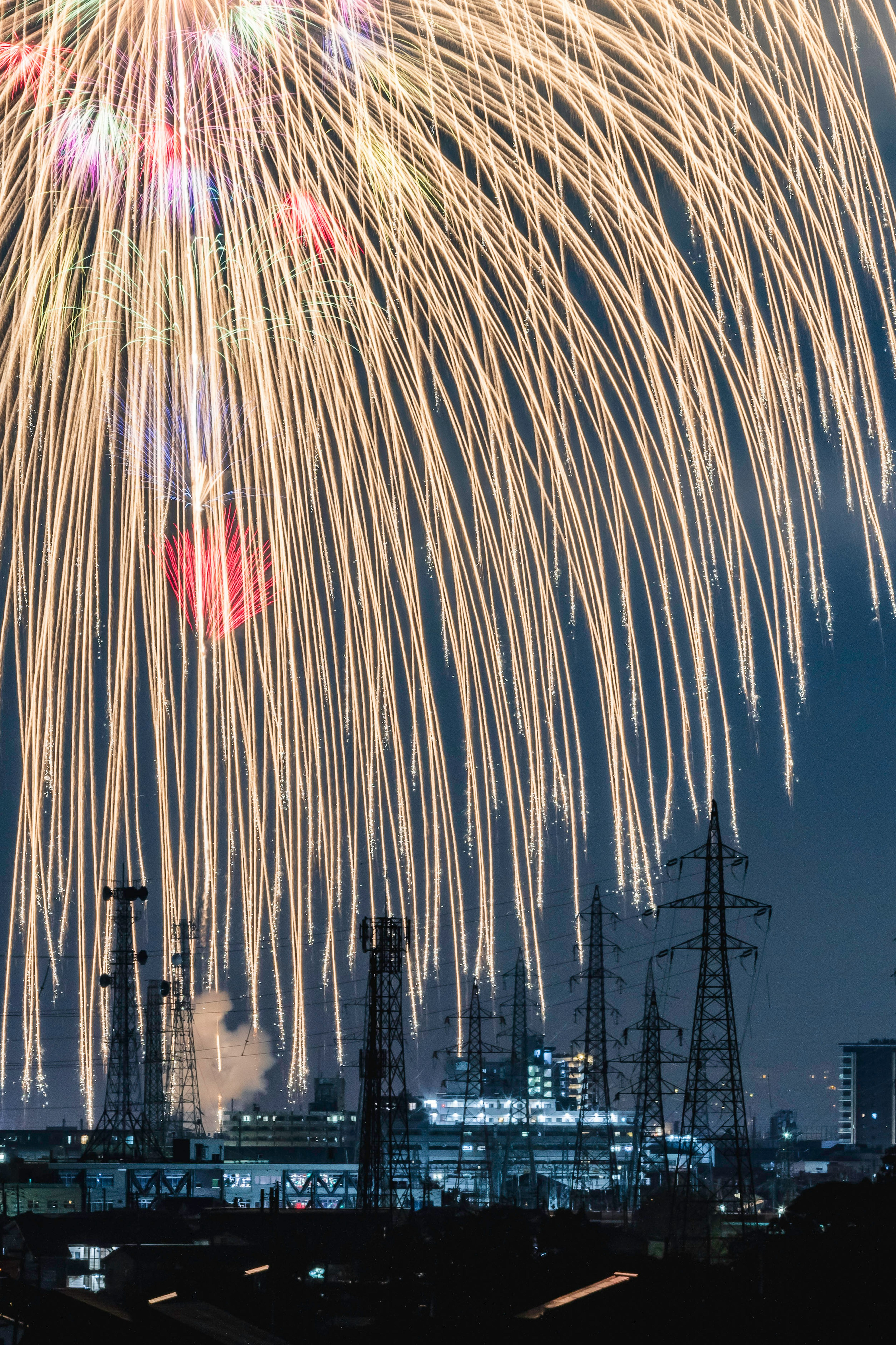 夜空を彩る花火と工場のシルエット