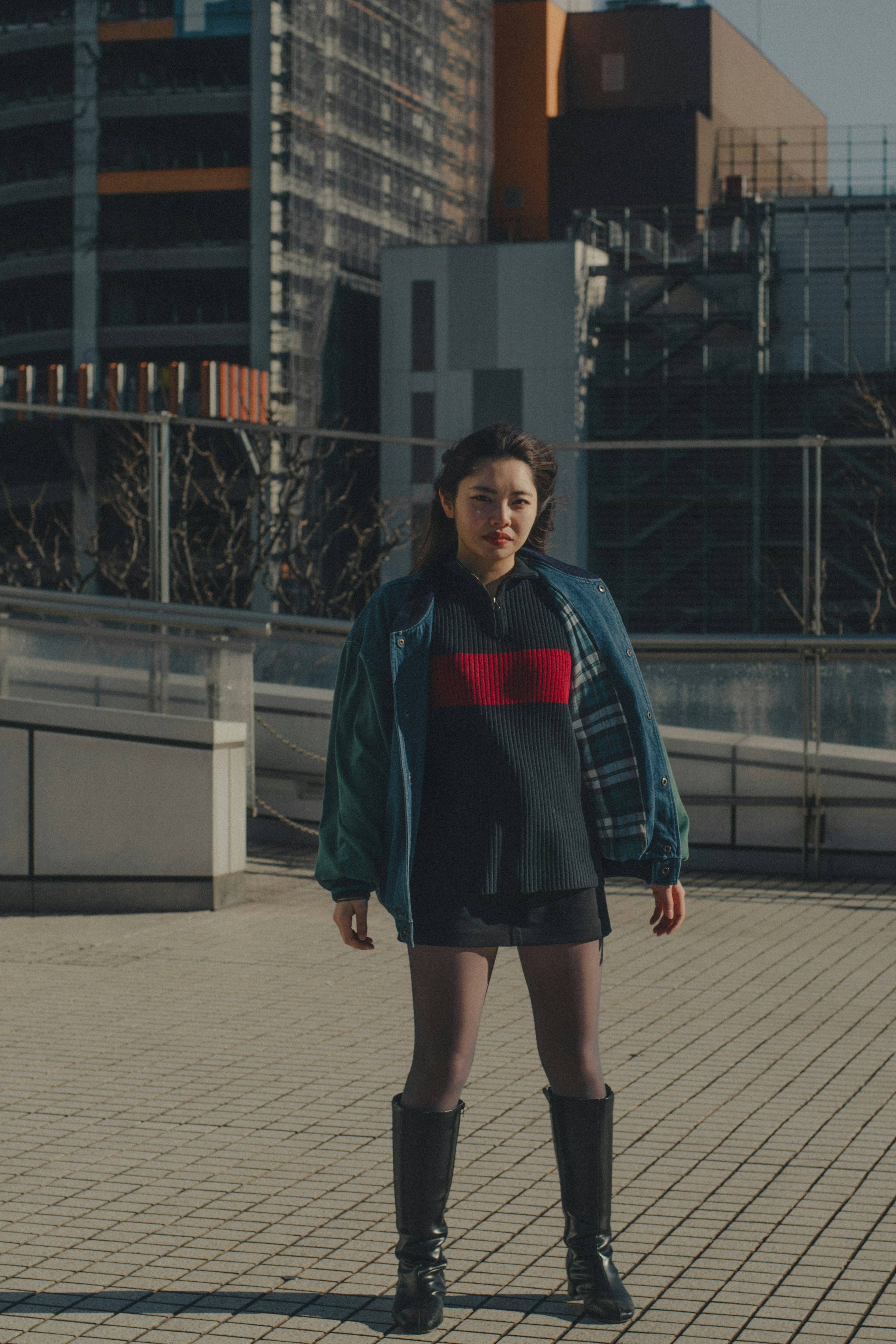 A woman posing on a rooftop fashion photo bright light and buildings in the background