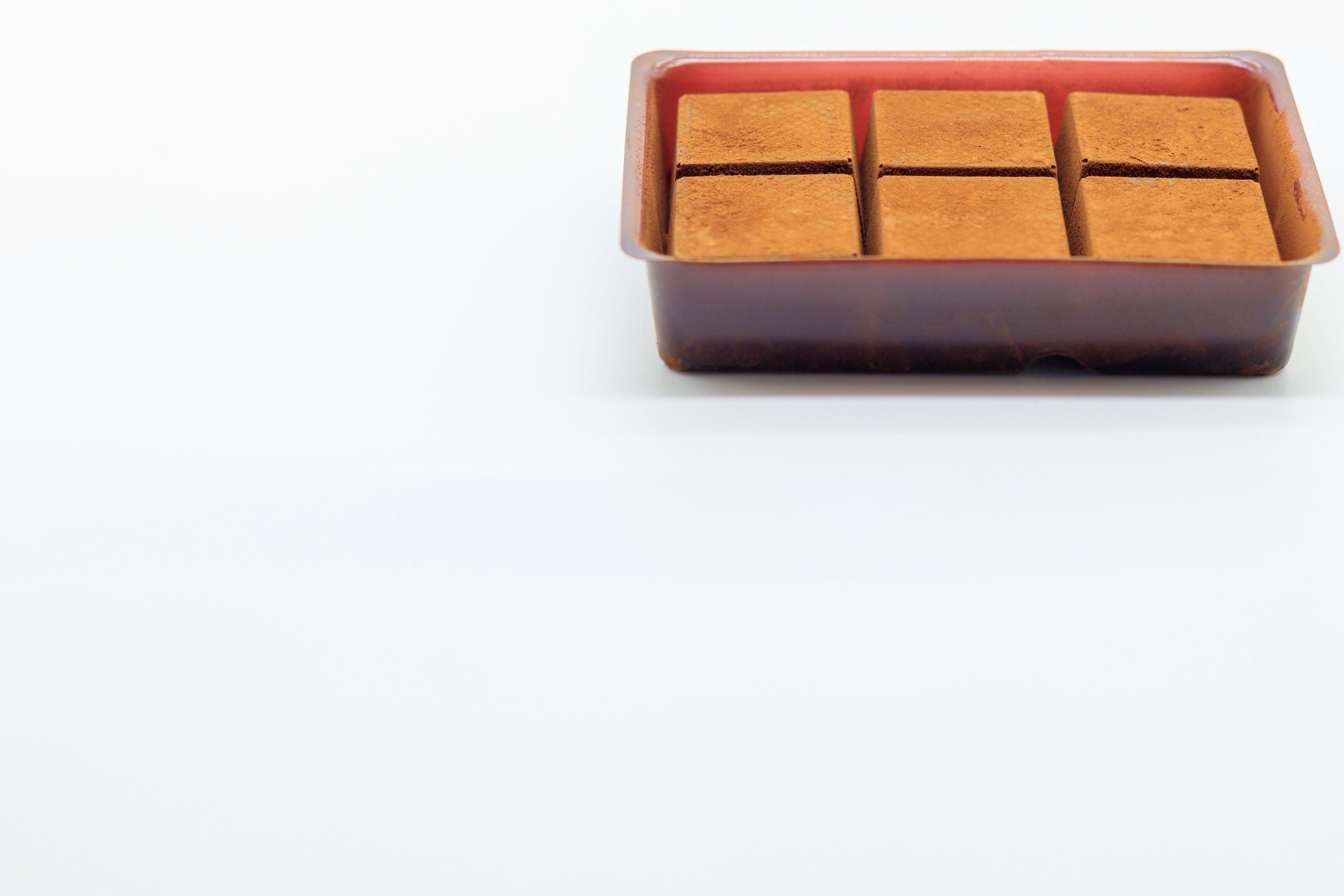 Plastic container with six square chocolate pieces