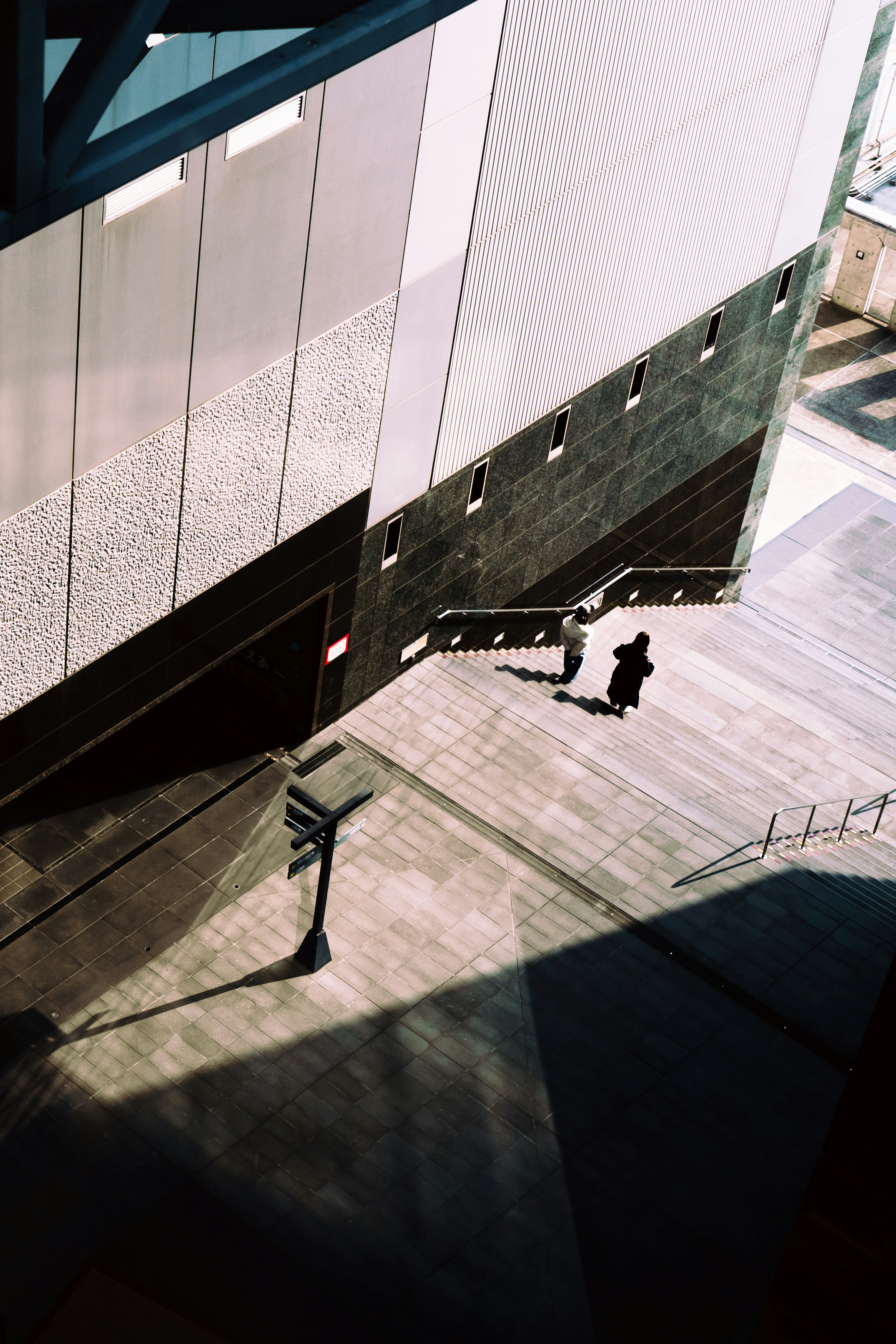 Shadow of a modern building with a person walking on the pavement