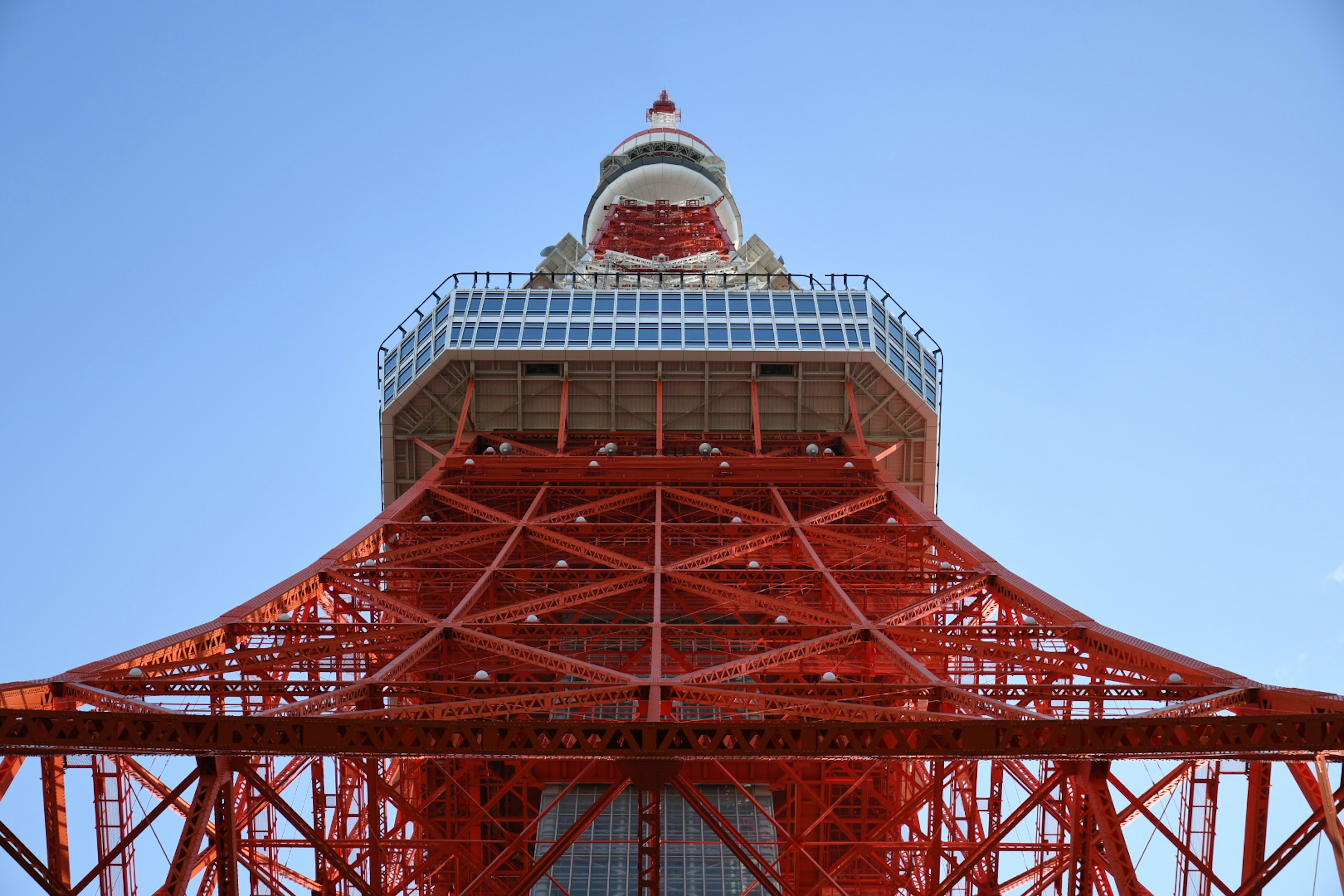 View of Tokyo Tower from below featuring red steel framework and blue sky