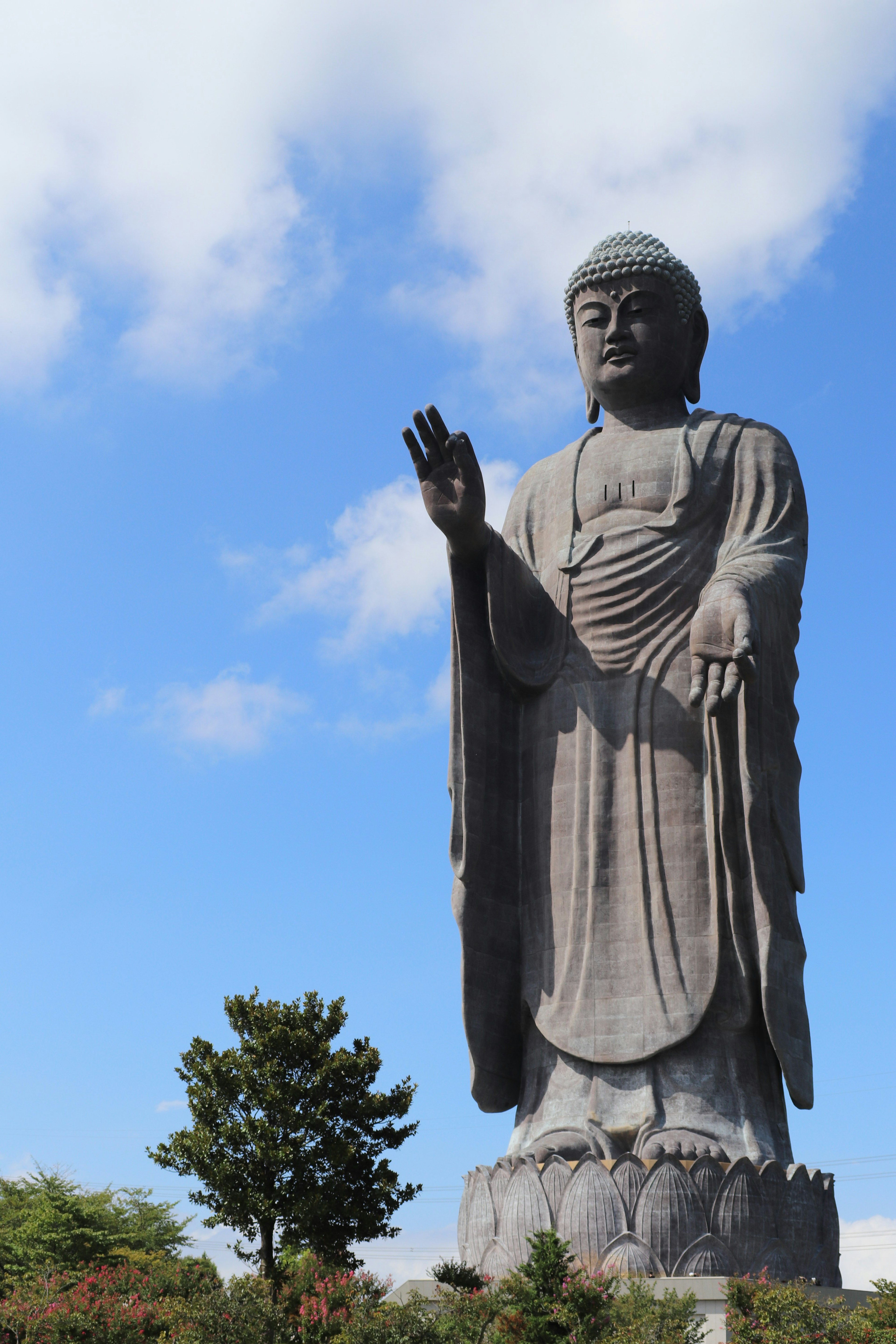 A giant Buddha statue standing under a blue sky