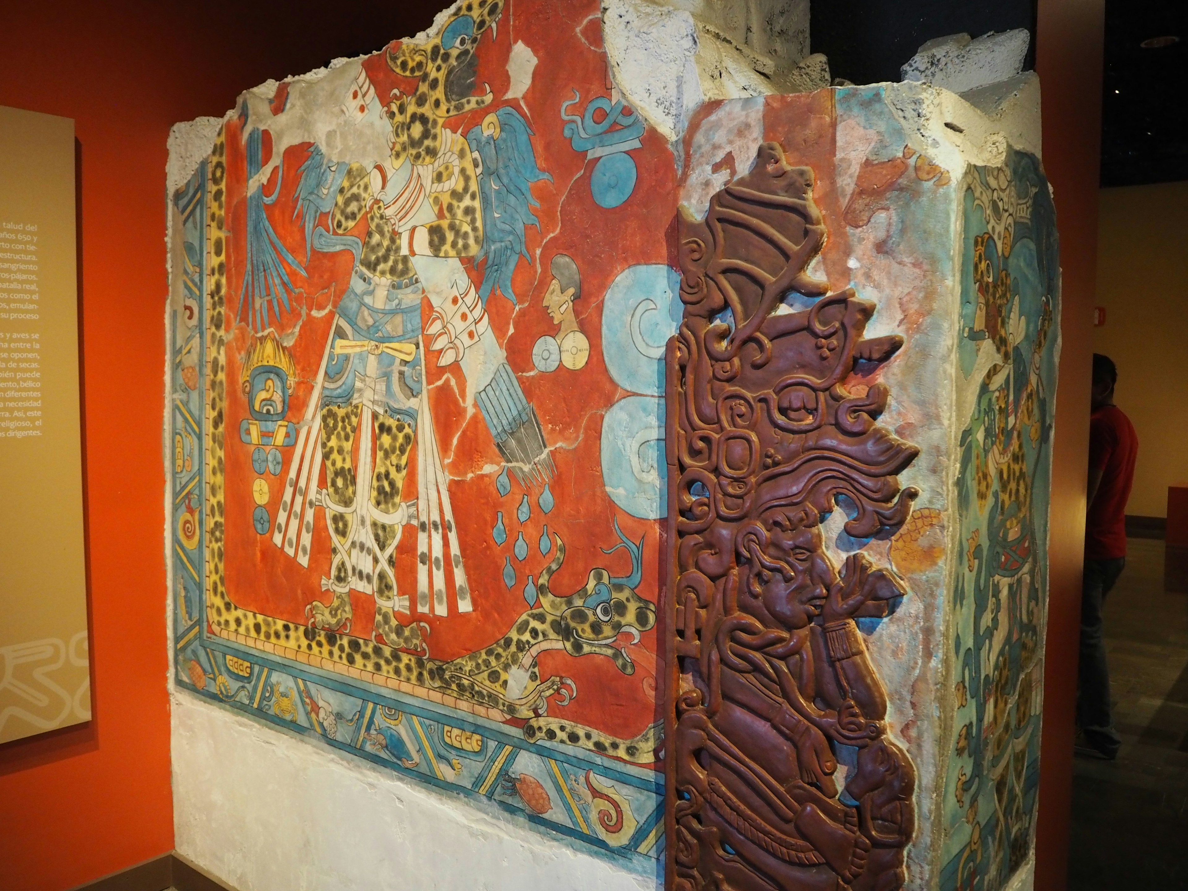 Mural antiguo colorido en una pared de piedra con intrincadas tallas en un museo