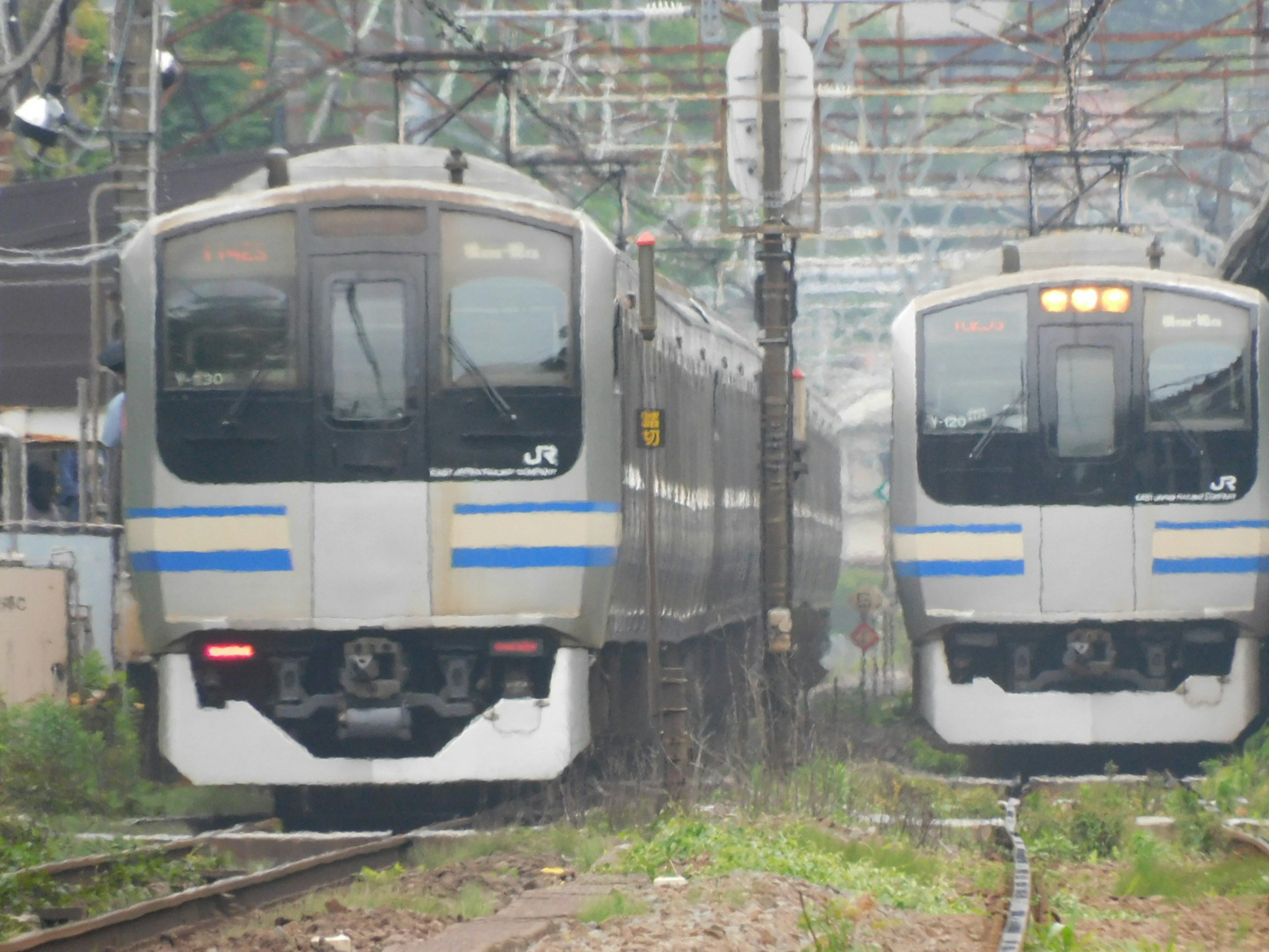 Two trains approaching on the tracks with surrounding railway infrastructure