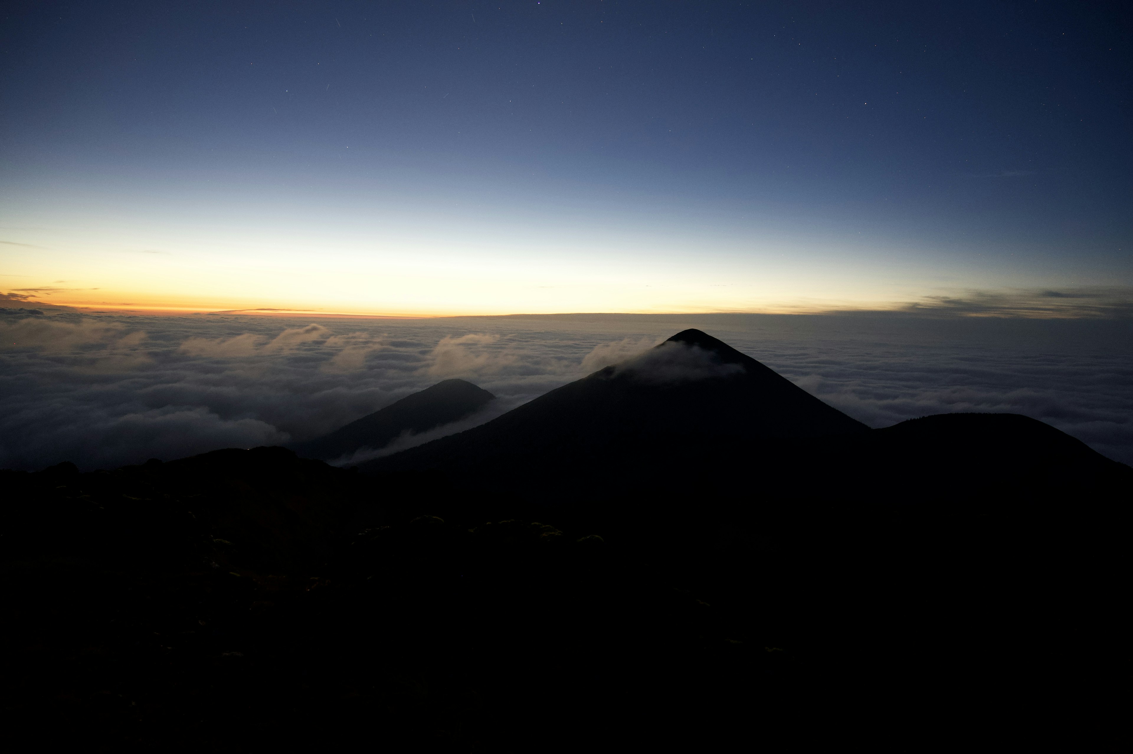 Silhouette di montagne contro un mare di nuvole all'alba