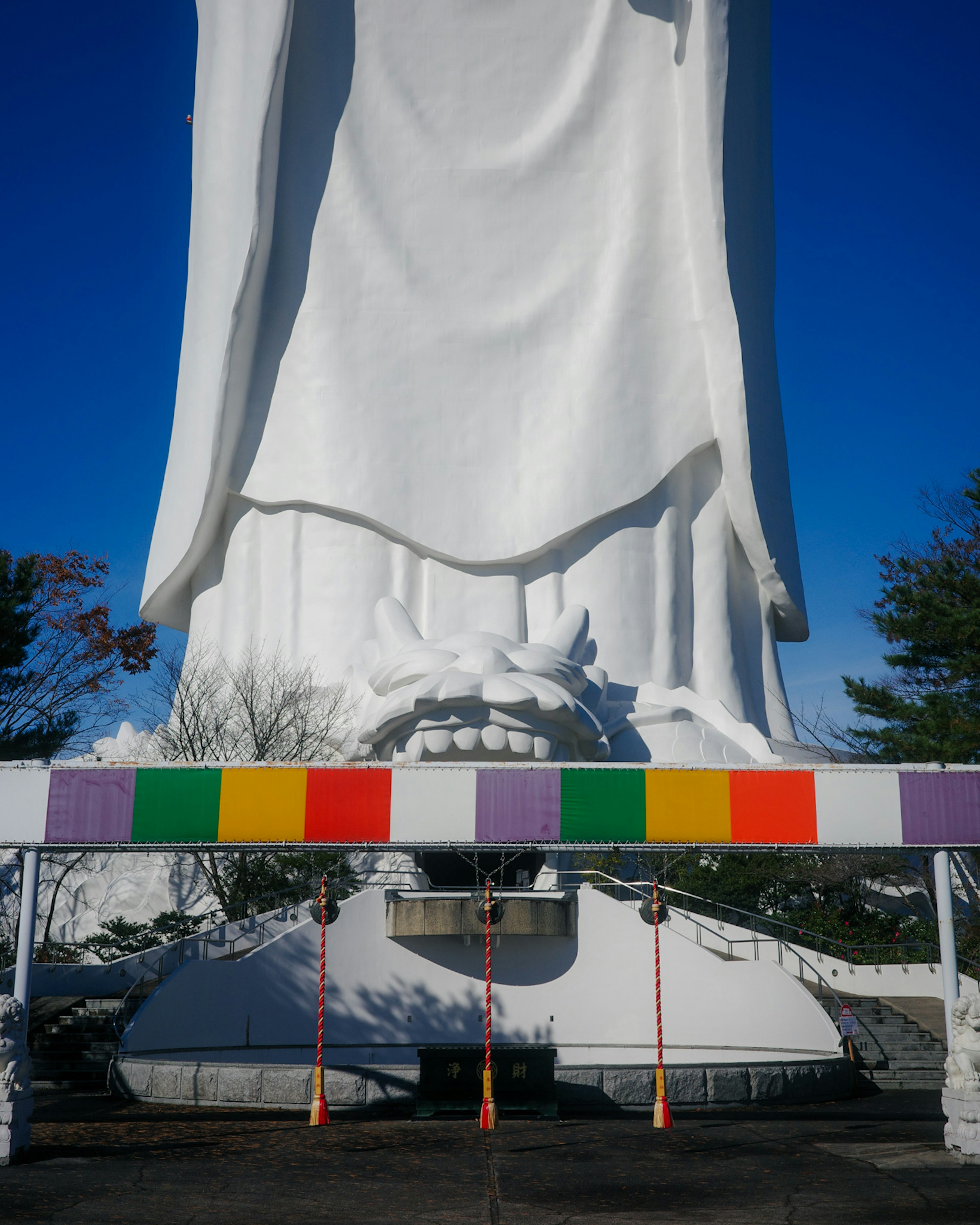 Gran estatua blanca con decoraciones coloridas debajo y cielo azul