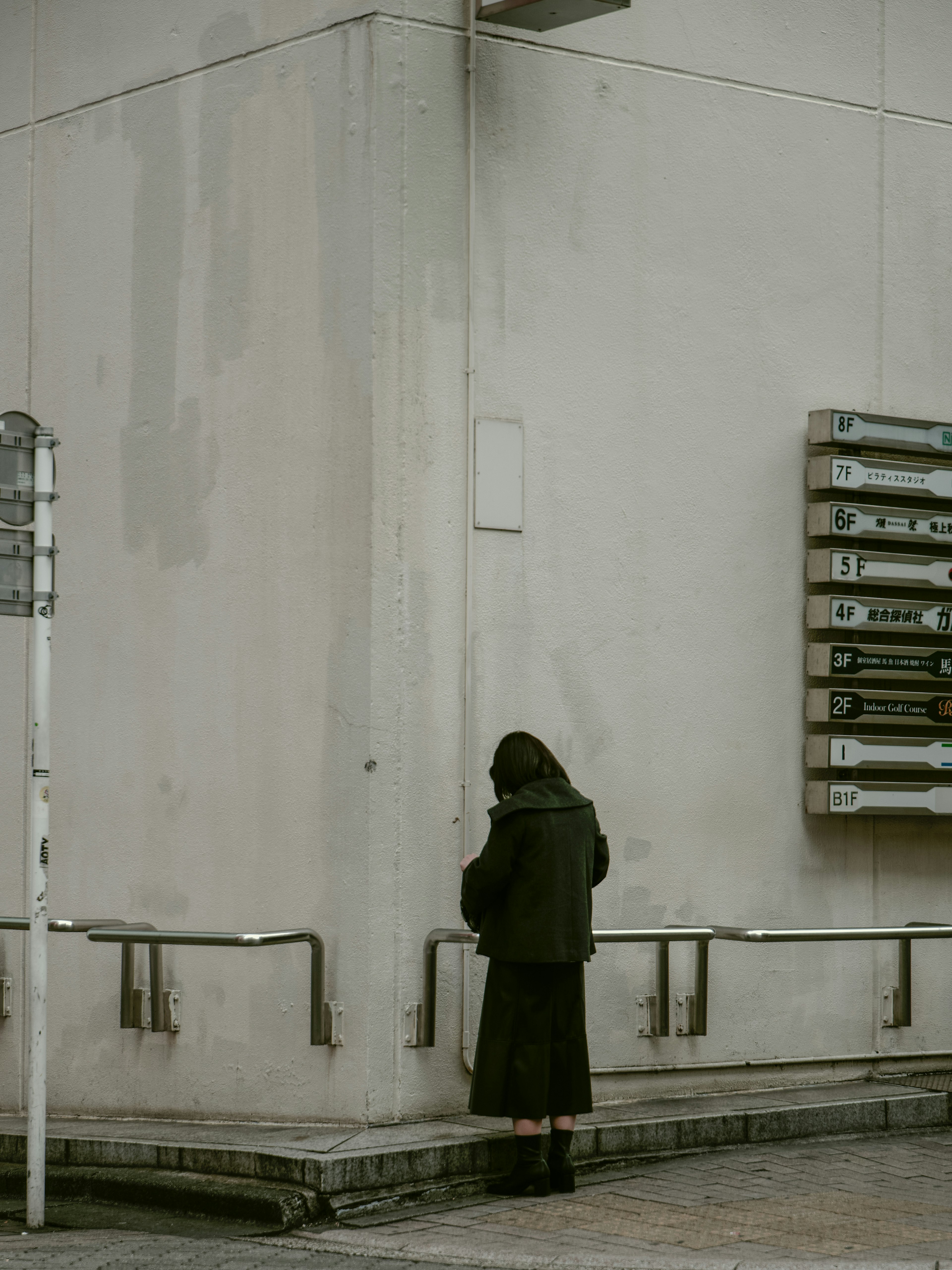 Eine Person steht vor einer Wand mit einem minimalistischen Gebäude im Hintergrund