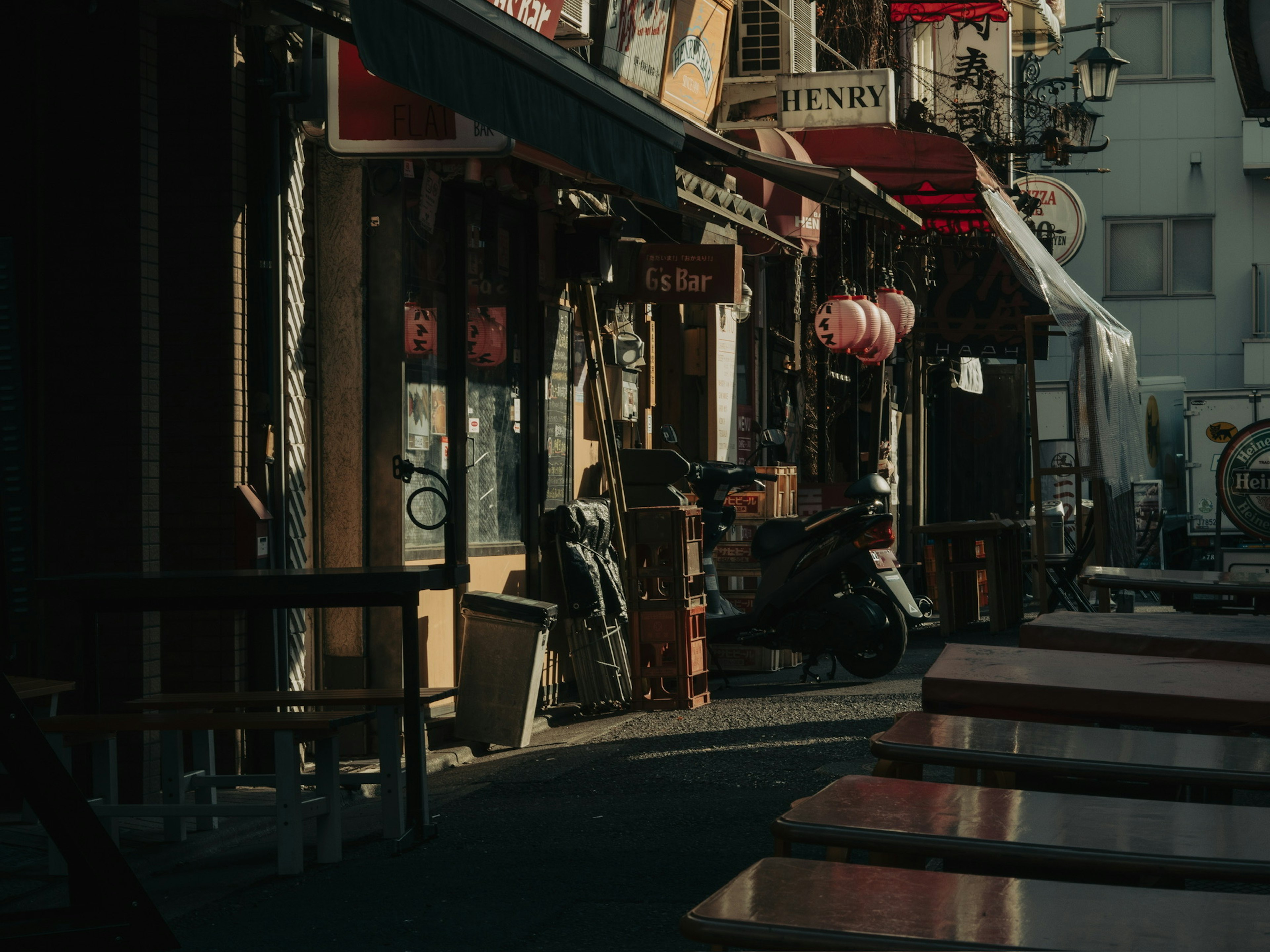 狭い通りに並ぶ小さな店舗とテーブルの風景