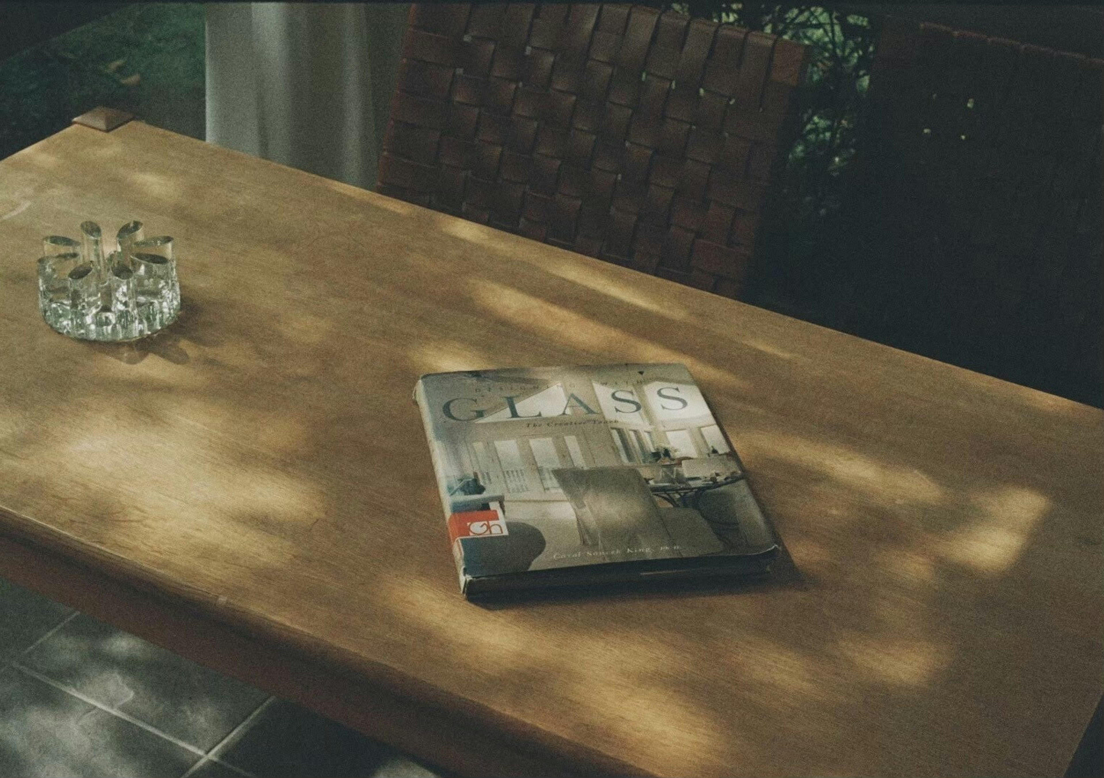 A magazine and an ashtray on a wooden table with beautiful light and shadow contrast