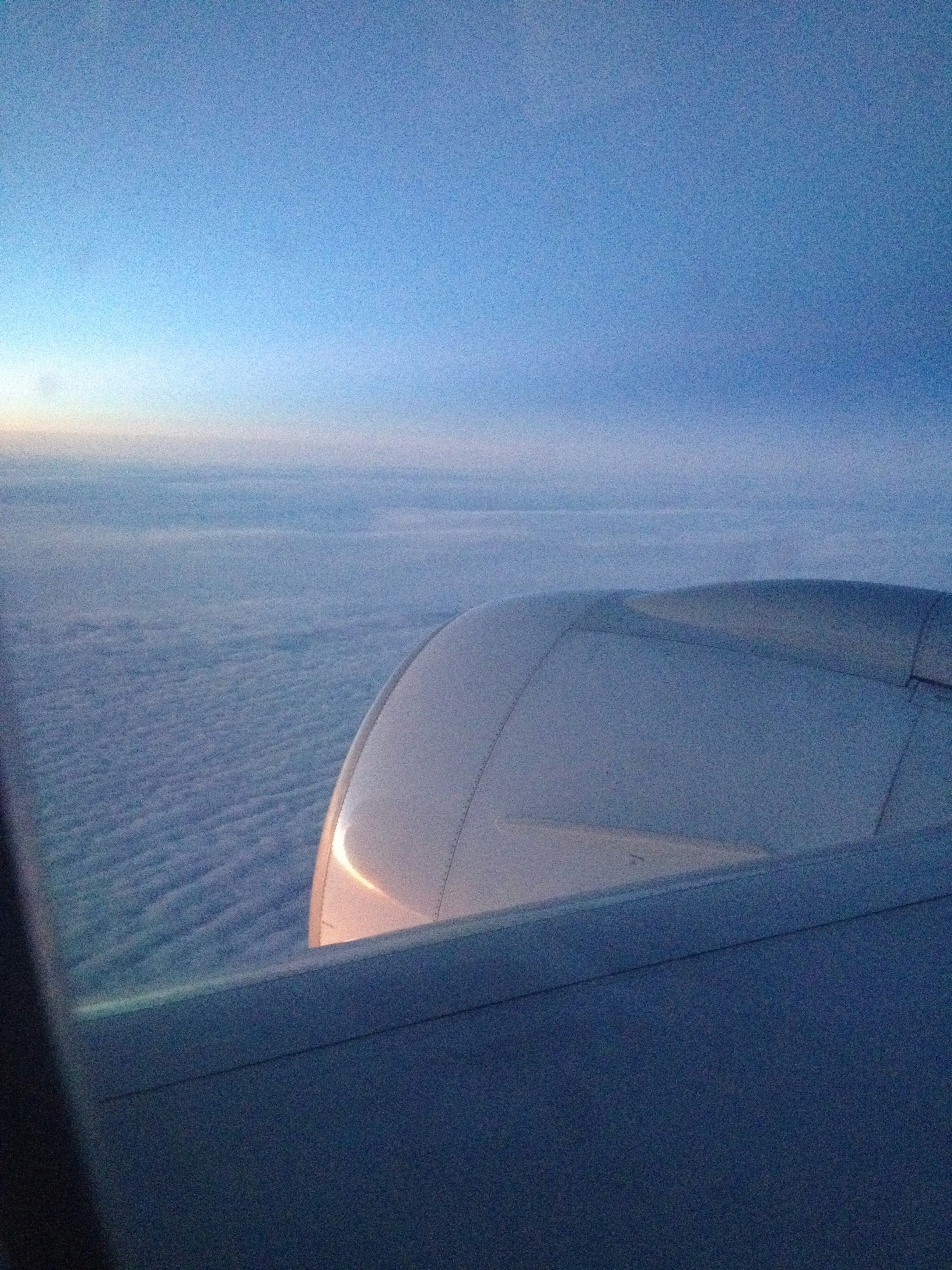 Vista da un finestrino d'aereo che mostra nuvole e cielo blu con un motore visibile