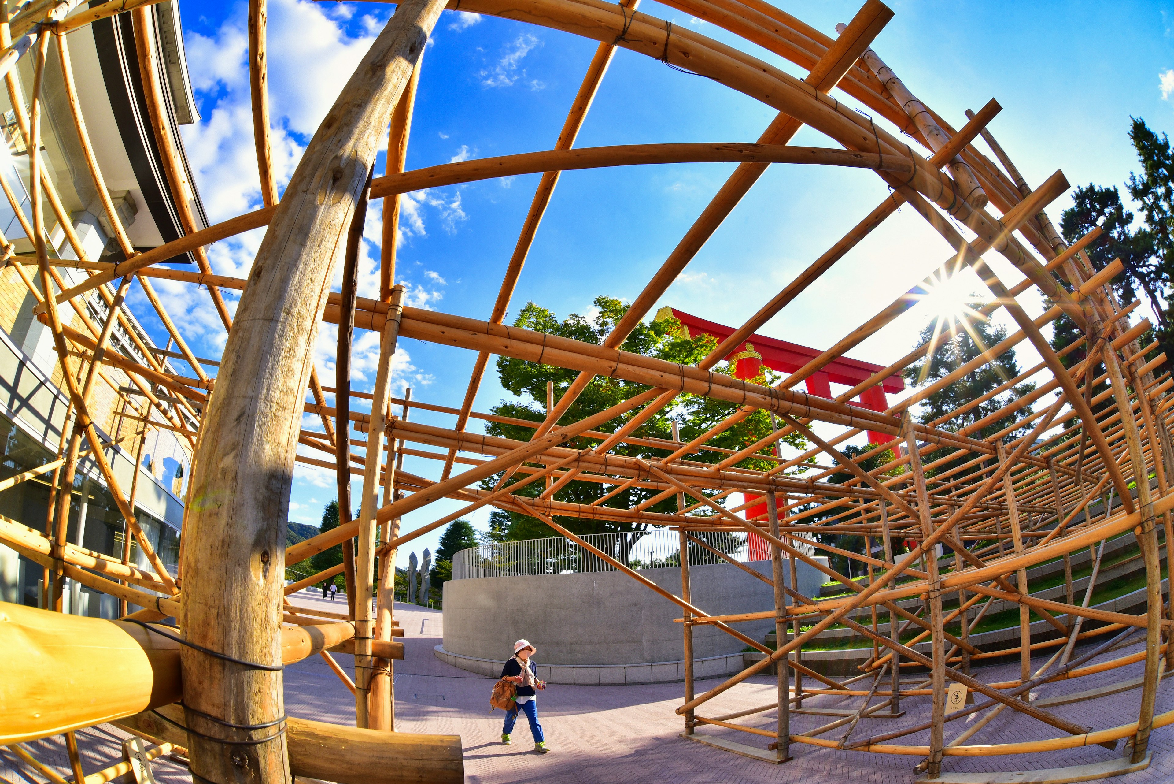 Child playing under a bamboo structure in a sunny outdoor setting