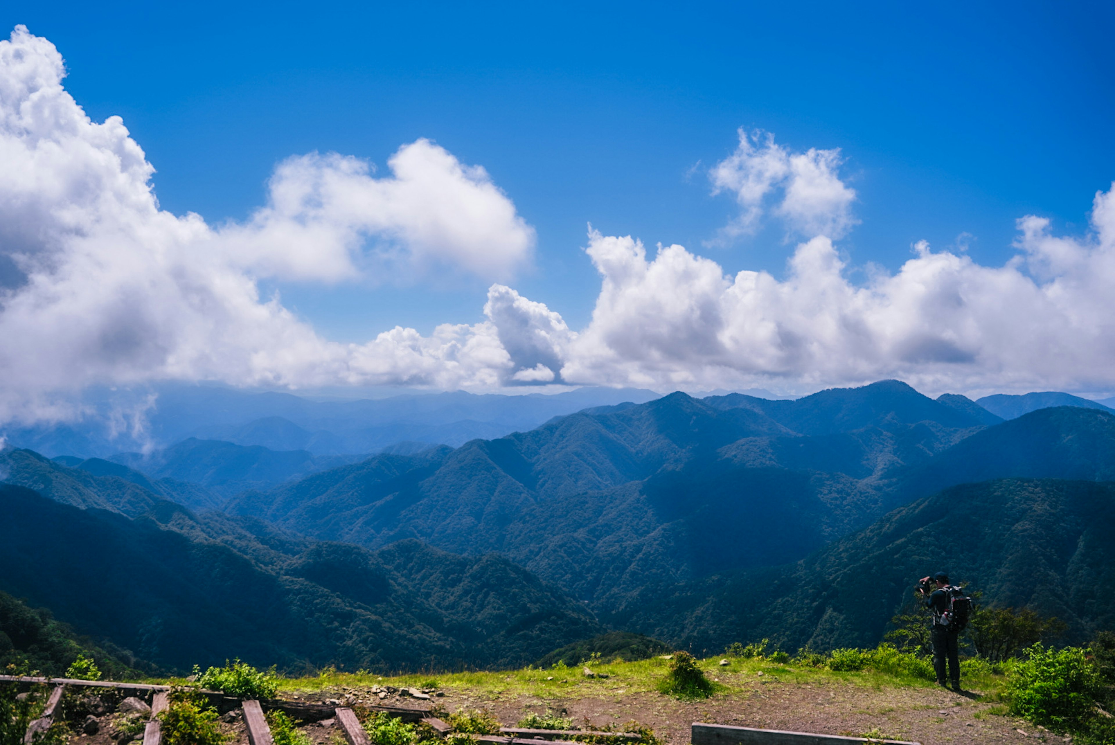 青い空と白い雲が広がる山の風景 人がカメラを持っている