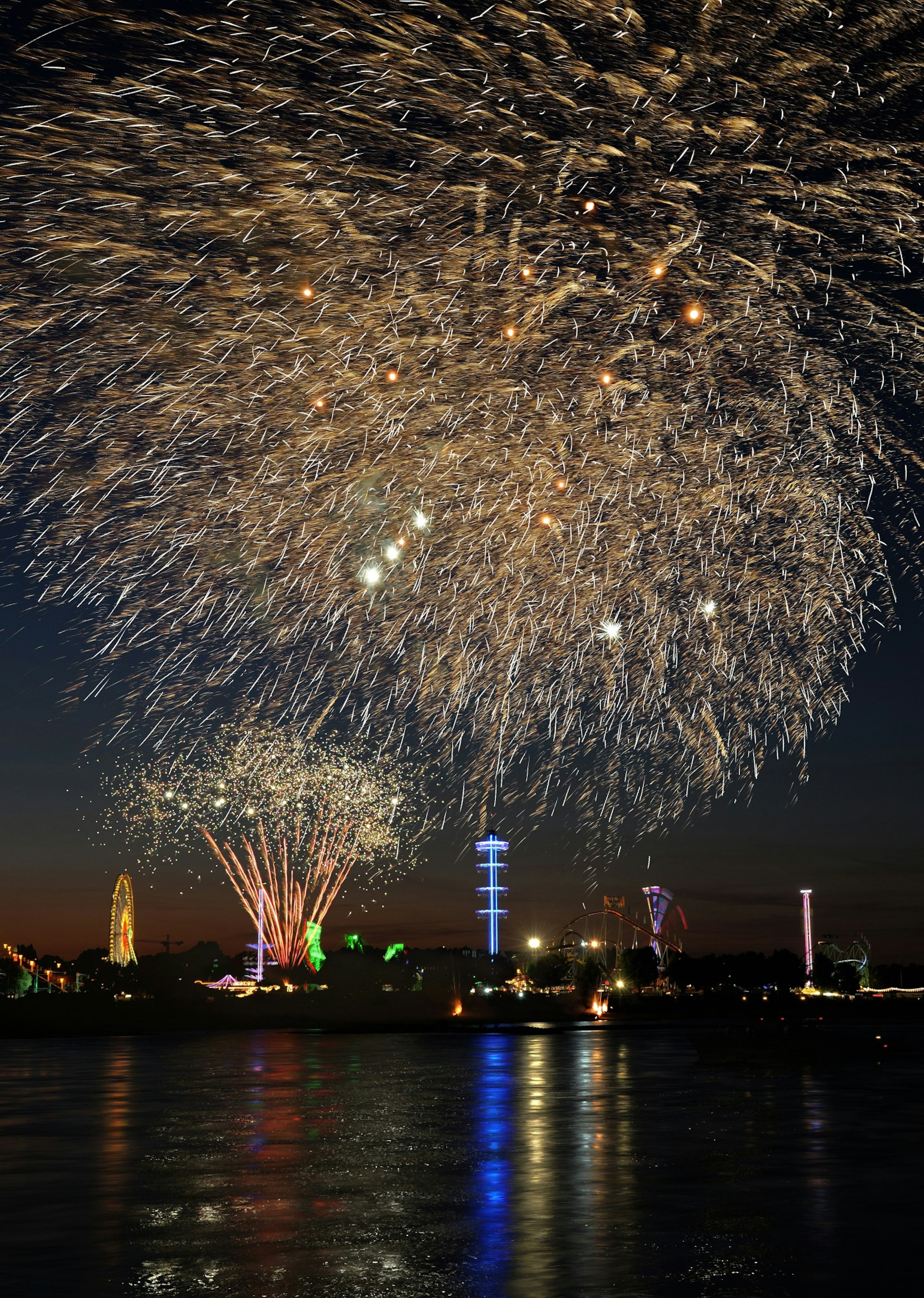 Espectáculo de fuegos artificiales iluminando el cielo nocturno con reflejos en el agua