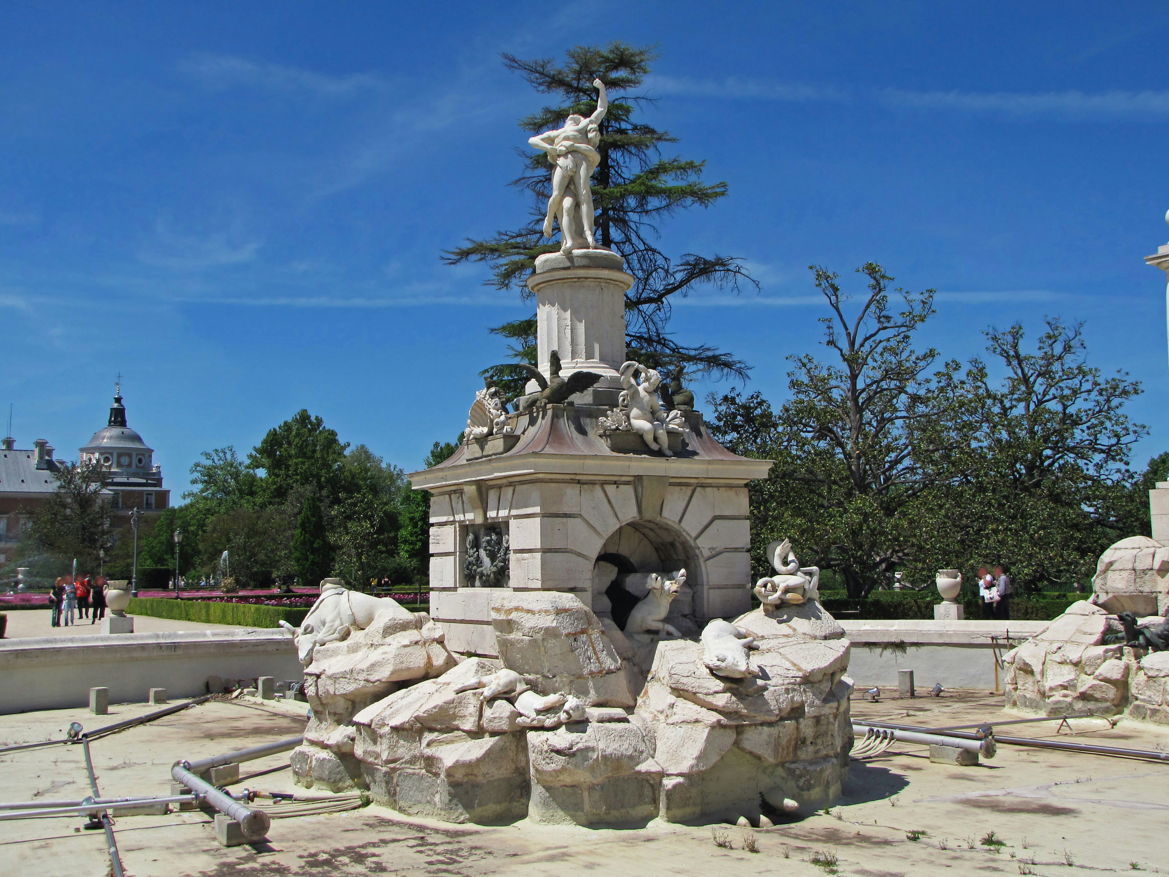 Parkszene mit einem Brunnen und einer zentralen Statue umgeben von Steinskulpturen