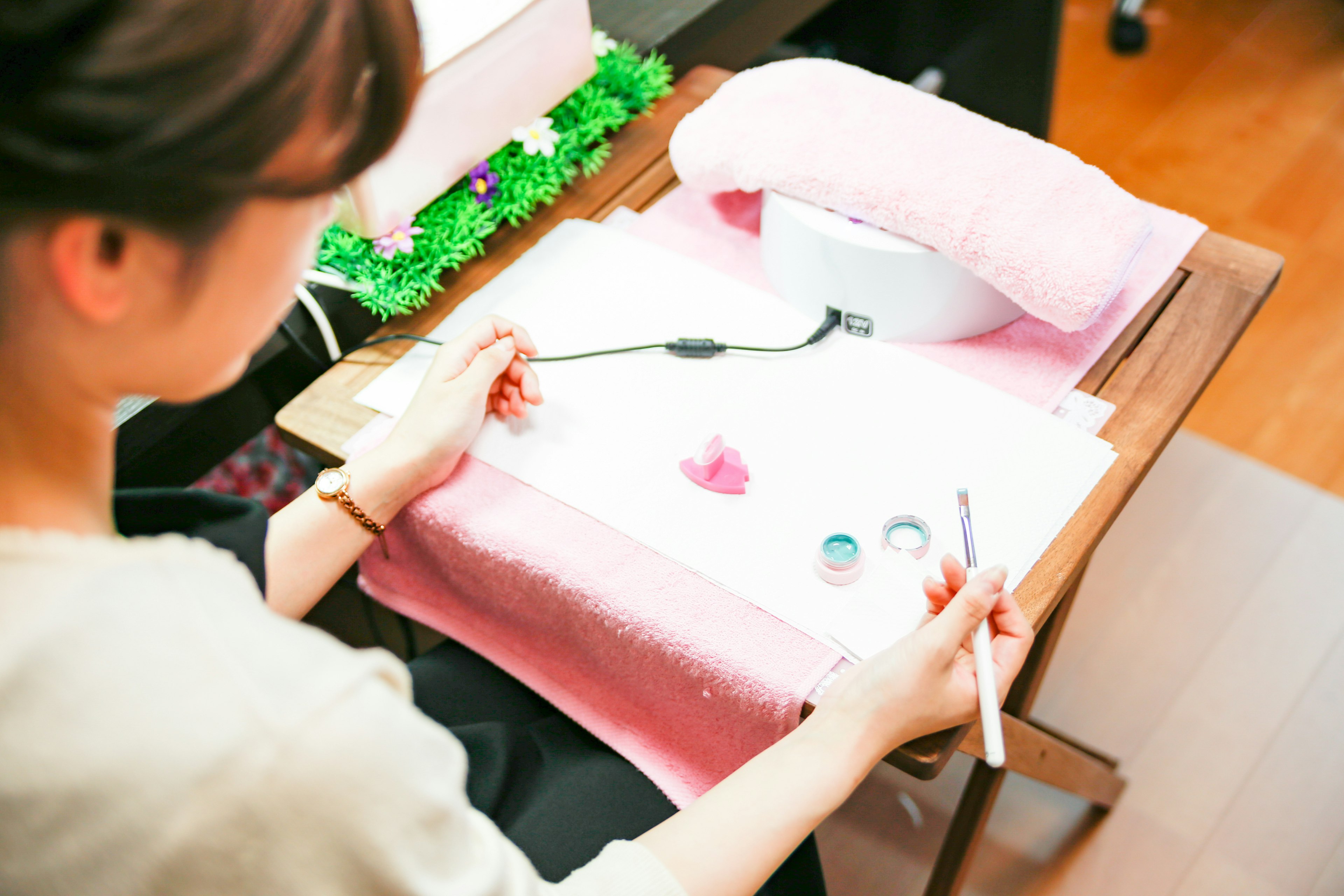 Eine Frau, die an Nagelkunst mit buntem Nagellack auf einem rosa Handtuch arbeitet