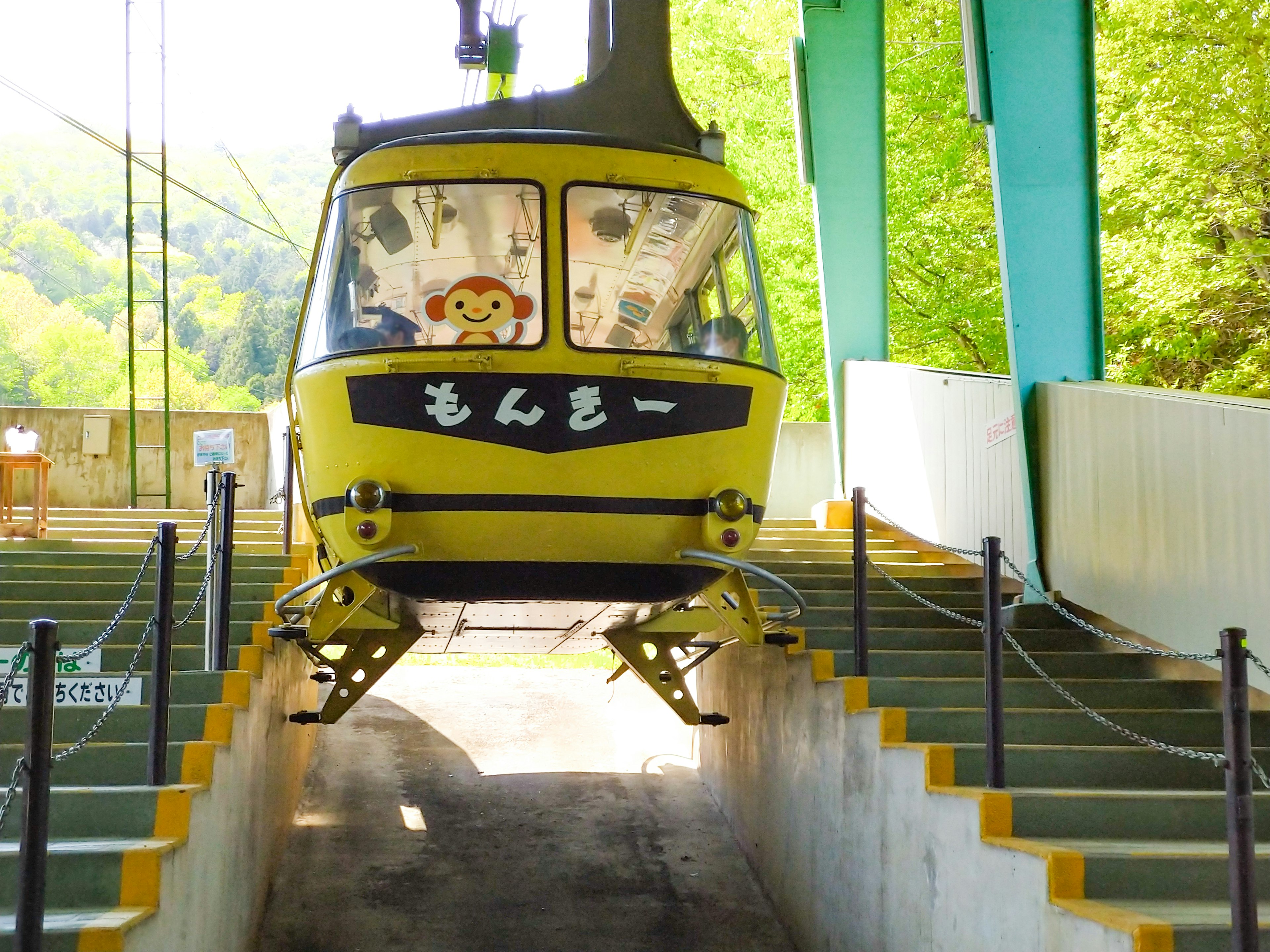 Teleférico amarillo llegando a la estación con un fondo verde