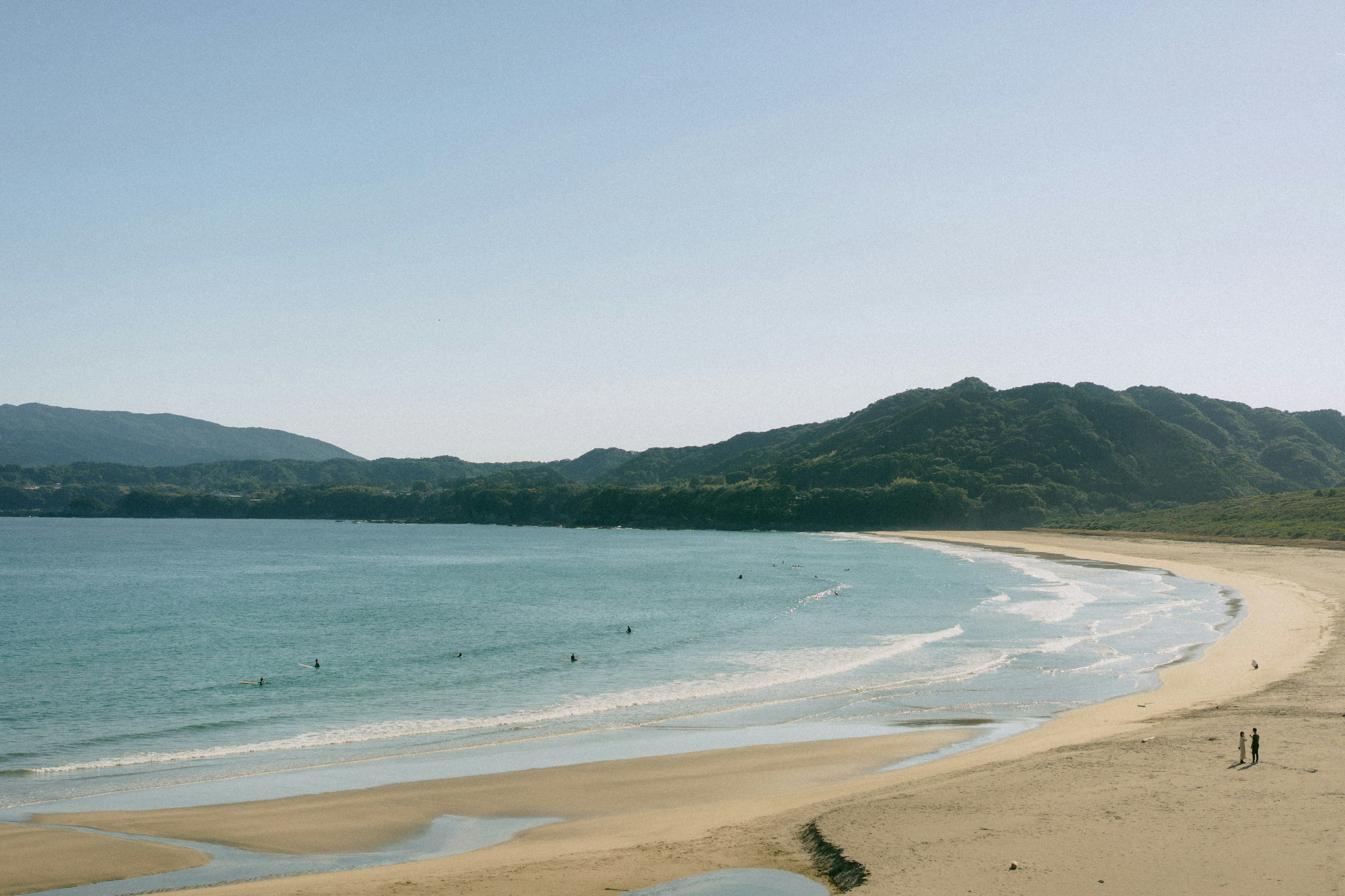 穏やかな海と緑の山々が広がるビーチの風景