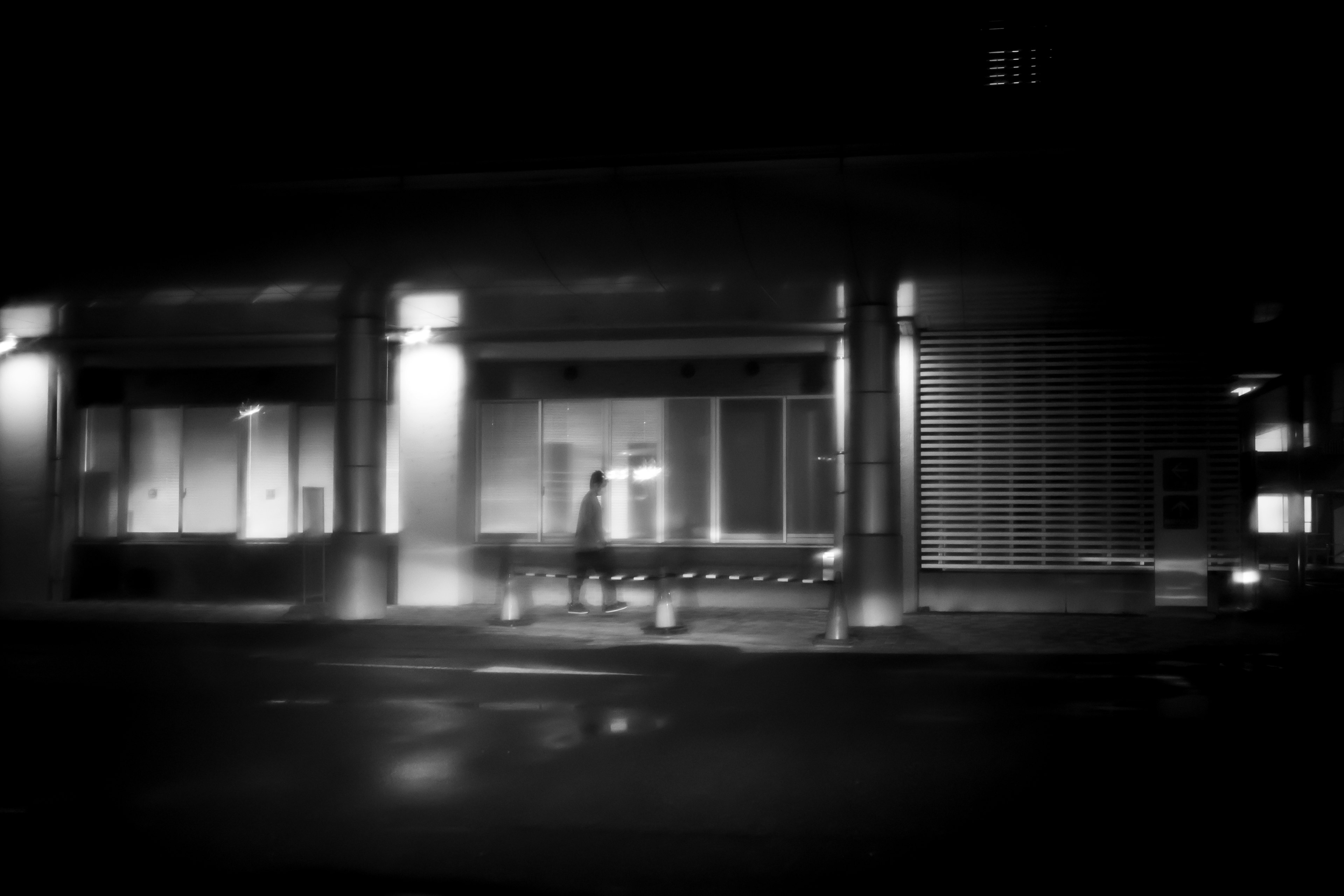 Silhouette of a building and bench on a dark street corner at night