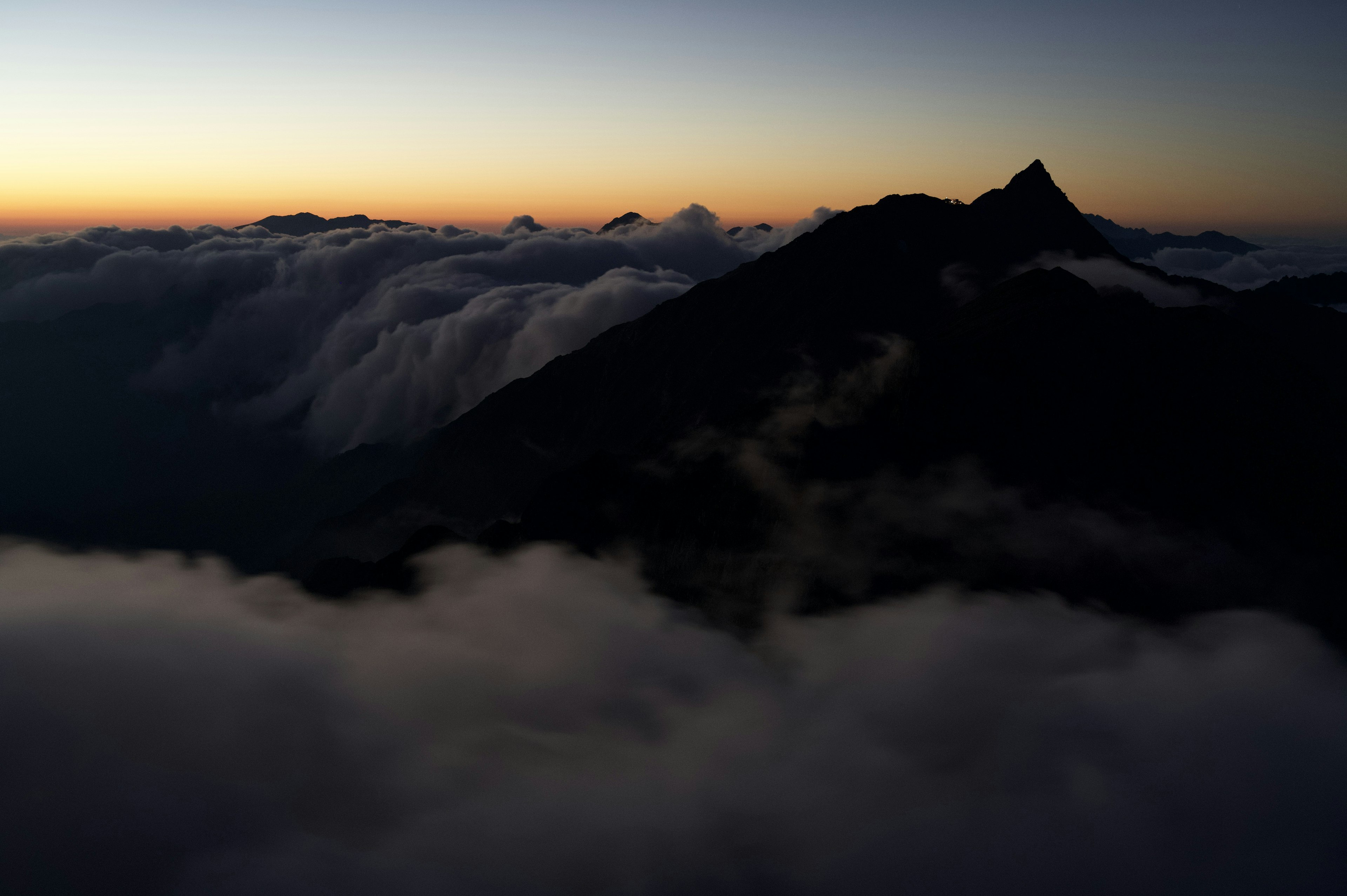 Silhouette von Bergen über den Wolken während eines schönen Sonnenuntergangs